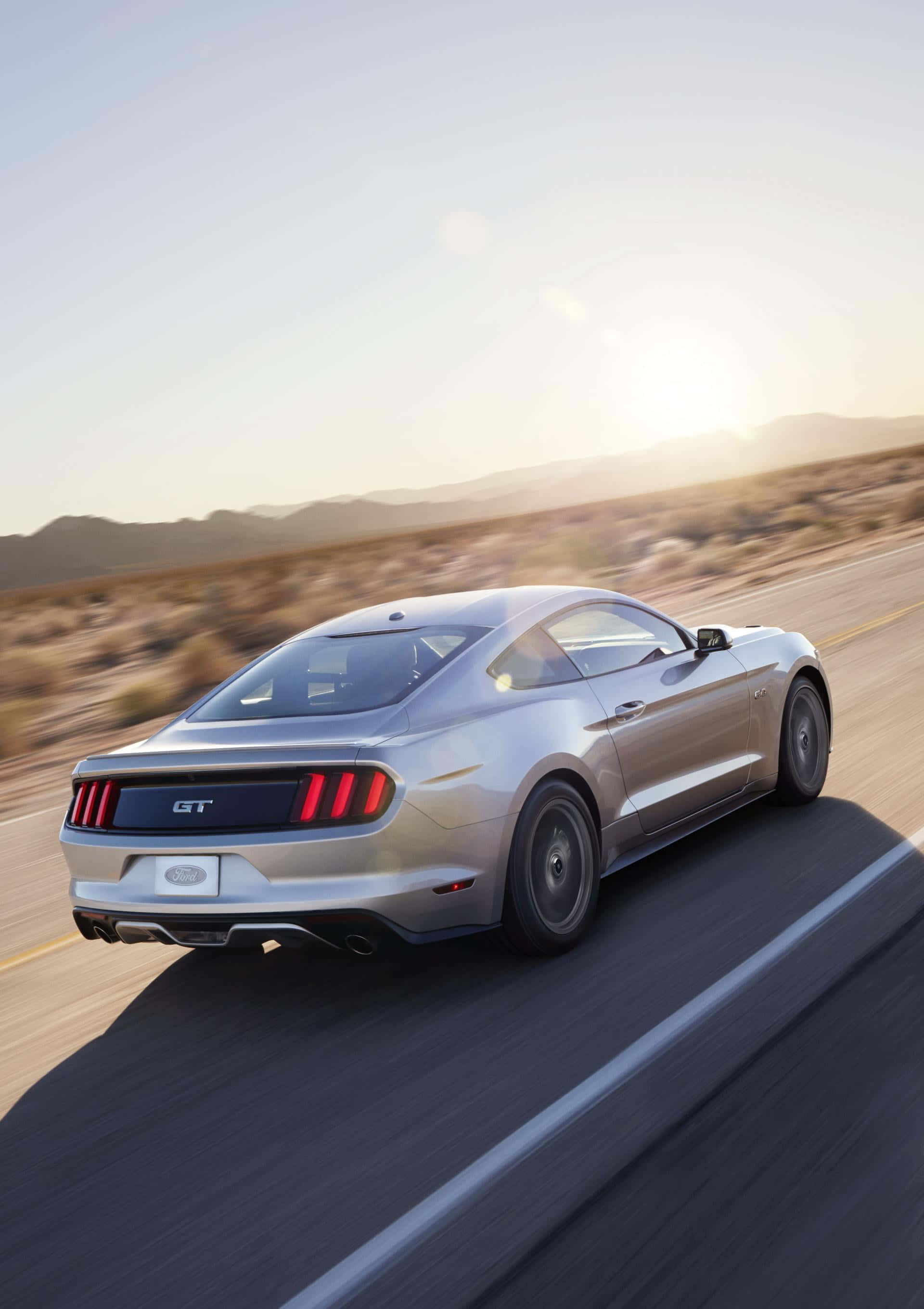 Ford Mustang California Special 桌布 壁紙 — 一輛銀色福特野馬GT在日落時分沿沙漠高速公路疾馳，帶有模糊動態和溫暖的金色光芒。