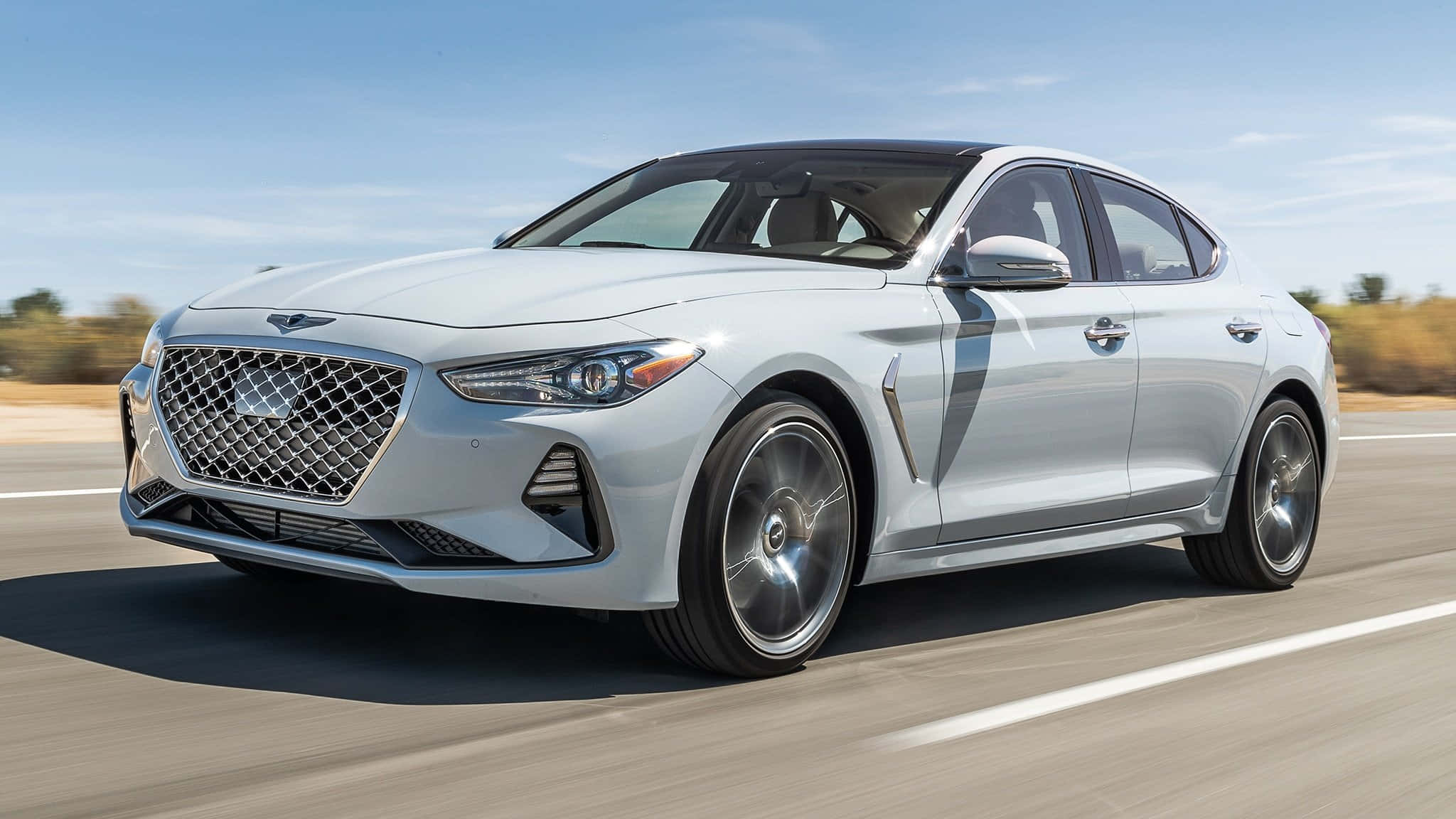 Genesis G70 桌布 壁紙 — 一輛時尚的銀色 Genesis 轎車在陽光明媚的高速公路上疾馳，背景是模糊的秋樹。