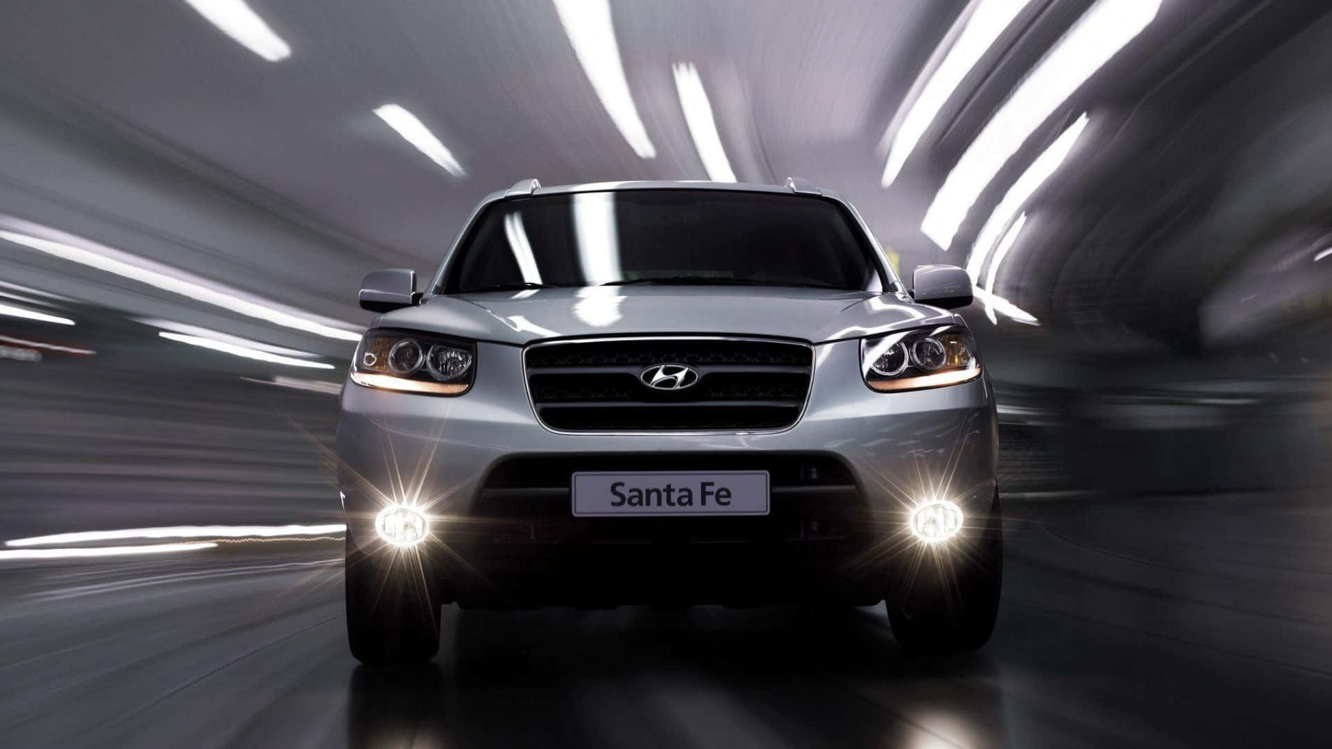 Hyundai Santa Fe 桌布 壁紙 — 一輛銀色現代Santa Fe SUV在隧道中疾馳，白色燈光模糊掠過。