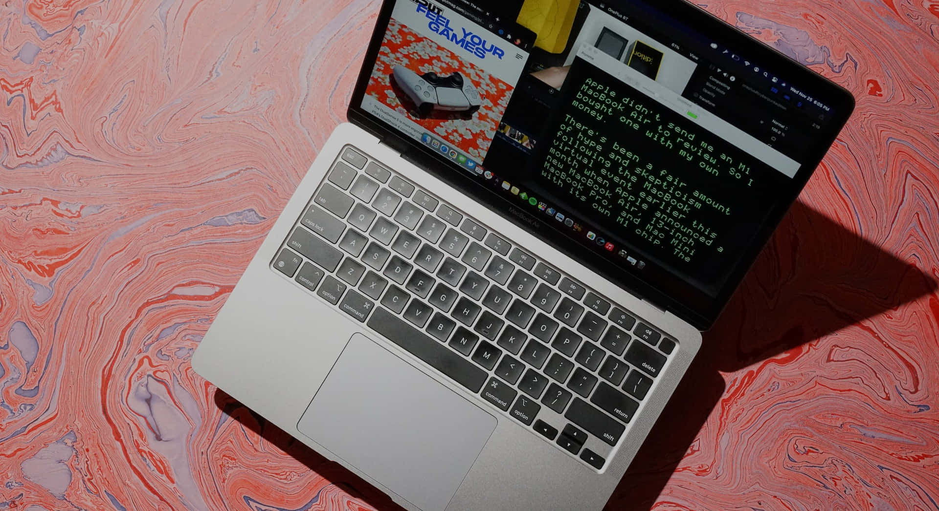 銀色筆記型電腦在彩色大理石表面上顯示遊戲和文字內容。 — Macbook Pro 壁紙