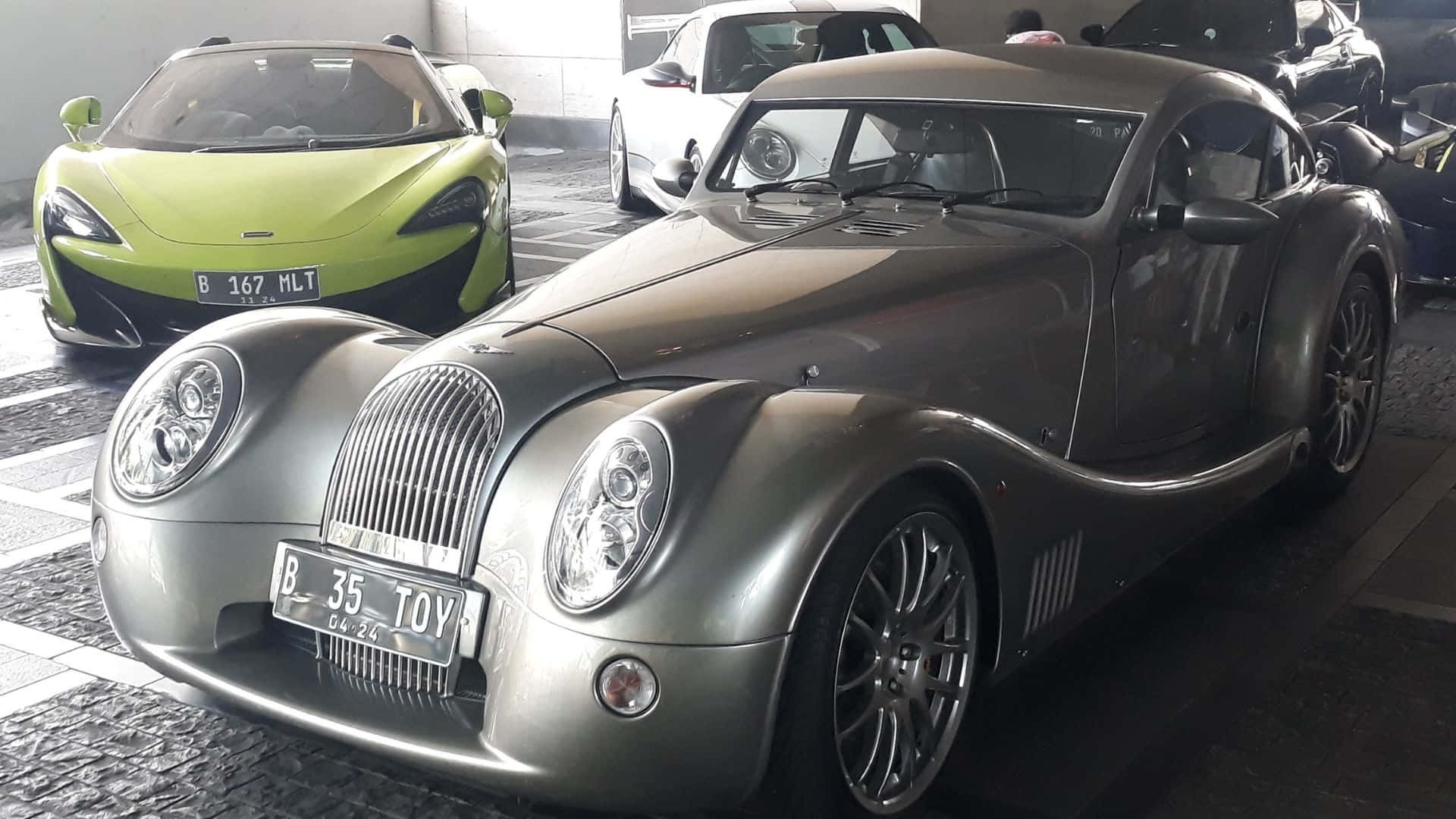 Morgan Aeromax 桌布 壁紙 — 一架時尚銀色復古風格摩根跑車醒目地停放在車庫中，旁邊是一輛充滿活力的萊姆綠色麥拉倫。