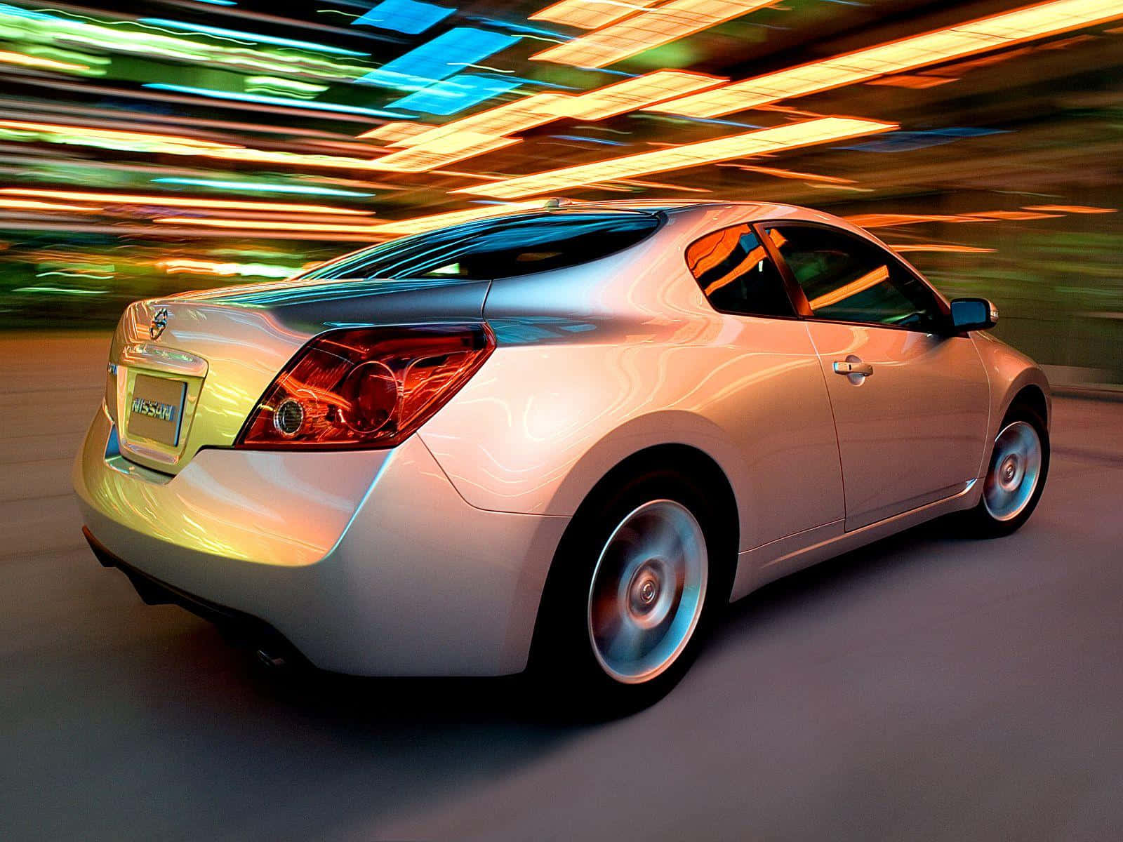 Nissan Altima 桌布 壁紙 — 一輛銀色日產轎跑車在霓虹燈閃爍的城市街道上飛馳，燈光形成動態的運動模糊效果。