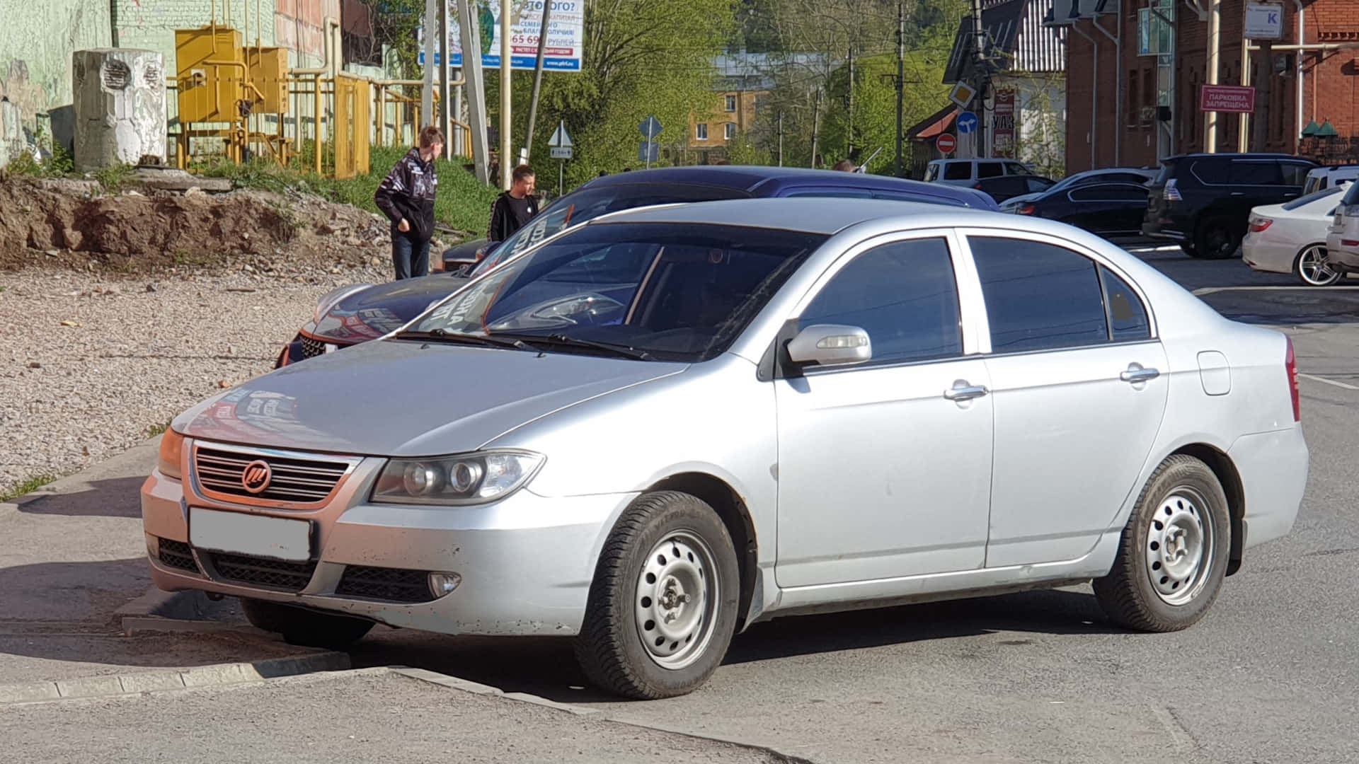  壁紙 — 一輛銀色轎車停放在陽光明媚的城市街道上，背景有行人和其他車輛。
