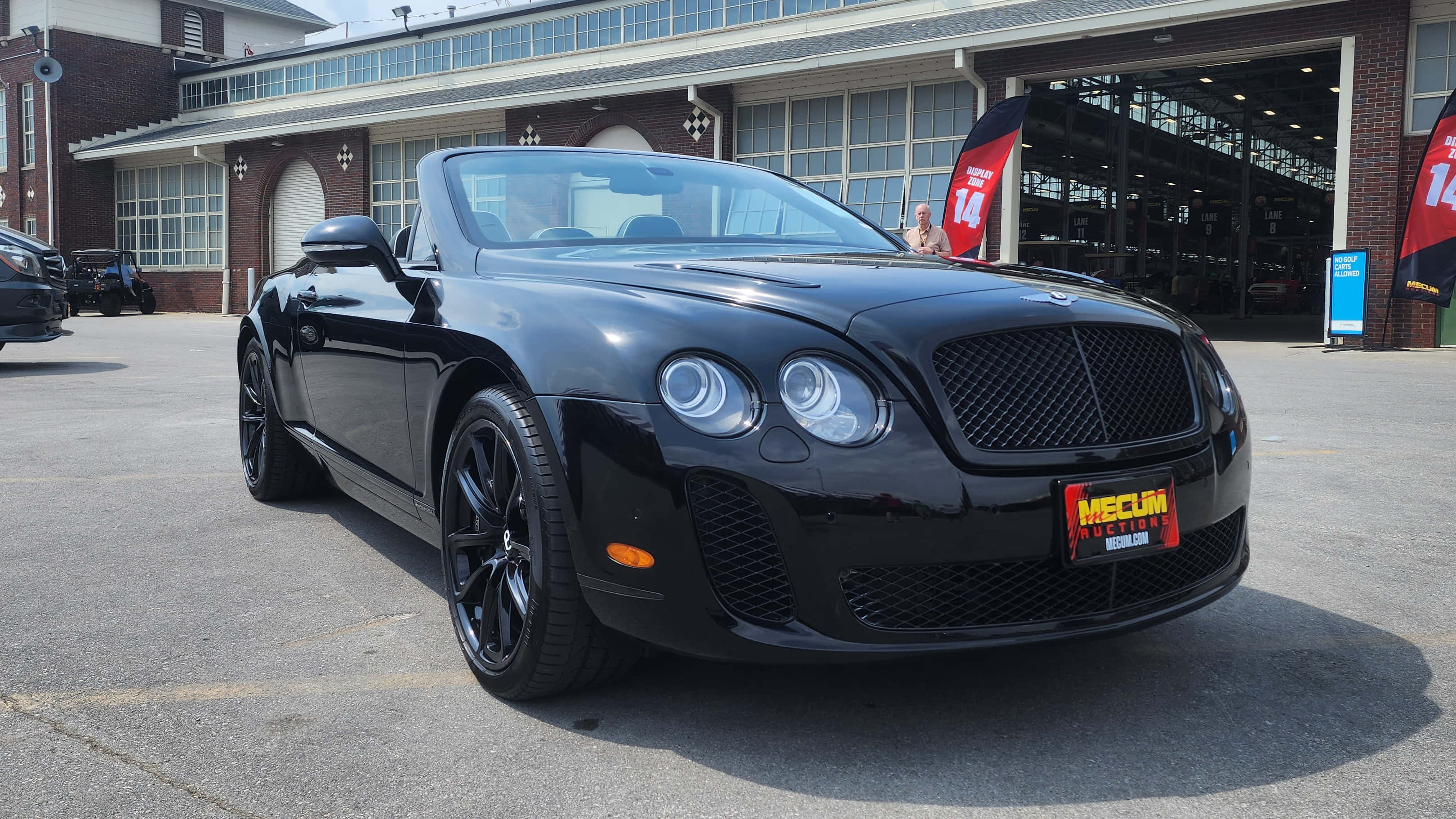 Bentley Continental Supersports 桌布 壁紙 — 一輛時尚的黑色賓利敞篷車停在磚砌車庫前，車庫有開放式車位和橫幅。