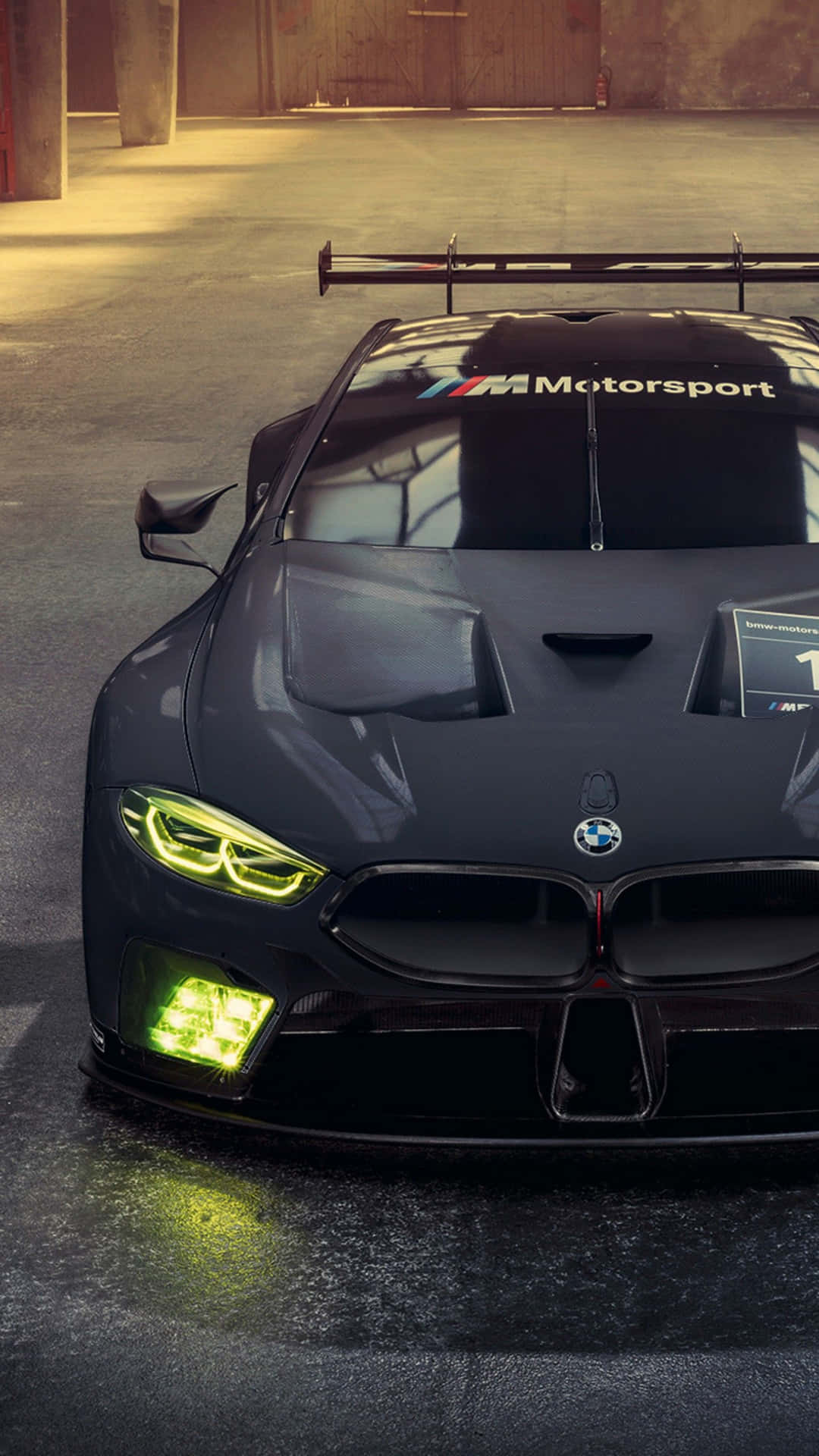 車庫中帶有綠色頭燈的黑色BMW賽車。 — 汽車 4K 壁紙
