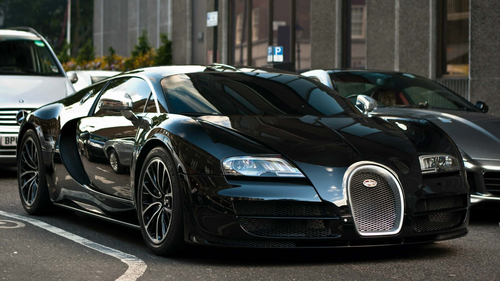 Bugatti Veyron 桌布 壁紙 — 一輛時尚的黑色Bugatti Veyron停泊在城市的街道上，反射出周圍的建築物和汽車。