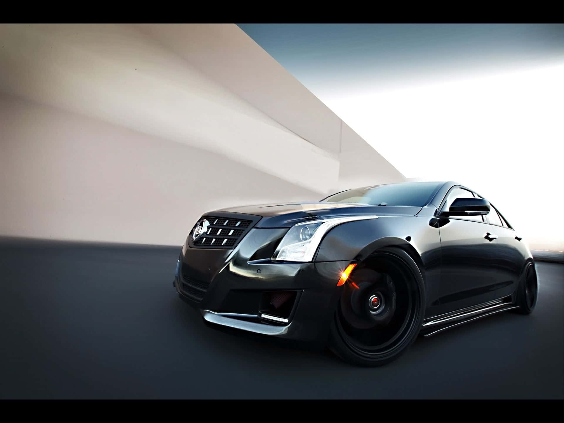 Cadillac Ats 桌布 壁紙 — 一輛時尚的黑色凱迪拉克ATS，帶有發光的橙色制動卡鉗，停在簡約的白色牆壁前，在明亮的日光下。