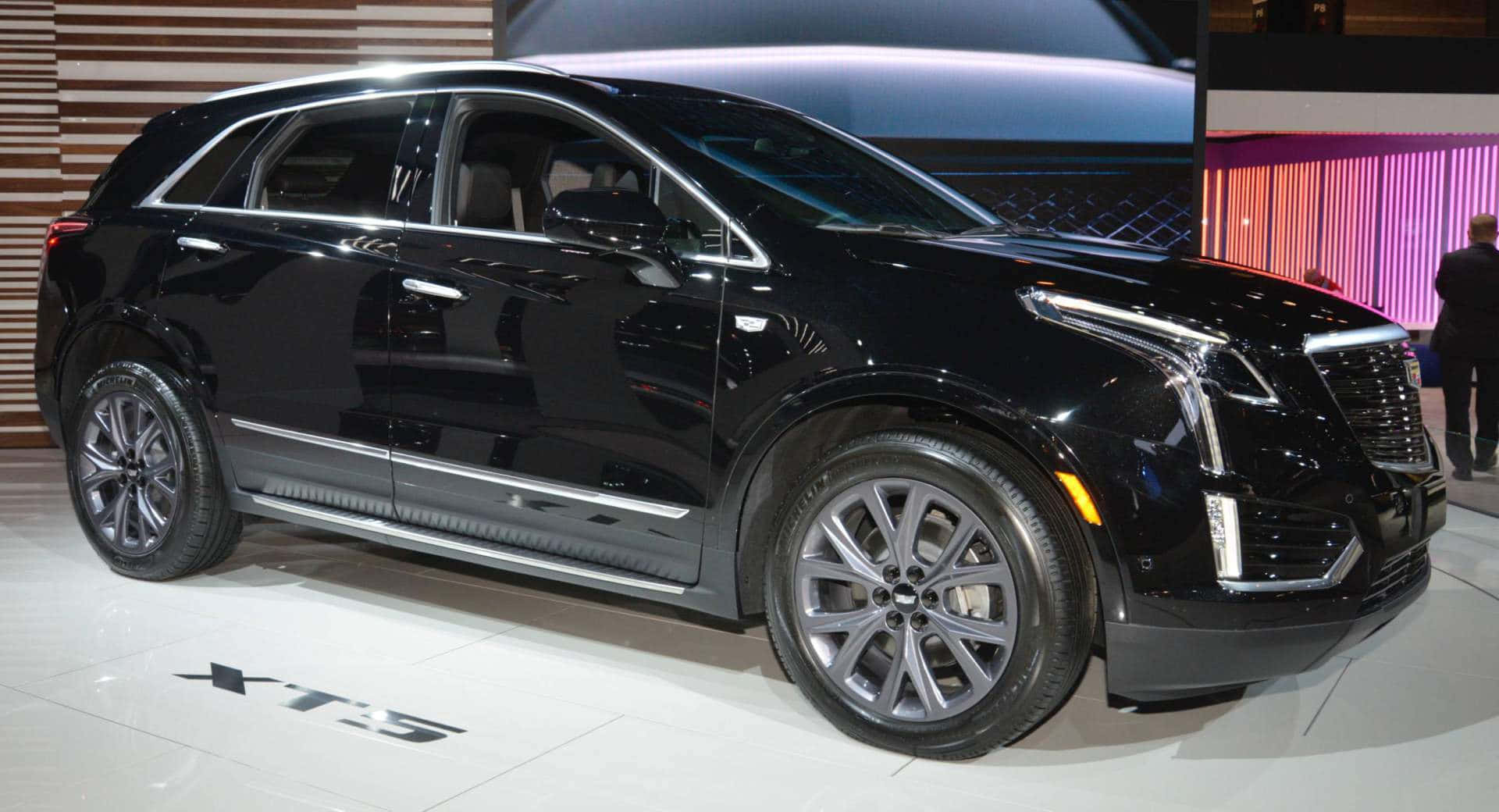 Cadillac Xt5 桌布 壁紙 — 一輛時尚的黑色 Cadillac XT5 SUV 在明亮的展廳燈光下閃閃發光，配備鍍鉻飾邊和時尚合金輪圈。