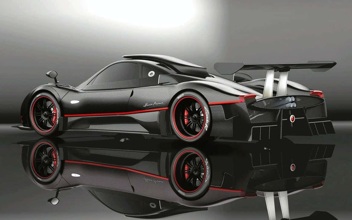 Pagani Huayra 桌布 壁紙 — 一輛時尚的黑色碳纖維跑車，帶有紅色點綴和大型後擾流板，在工作室燈光下展示在反光表面上。