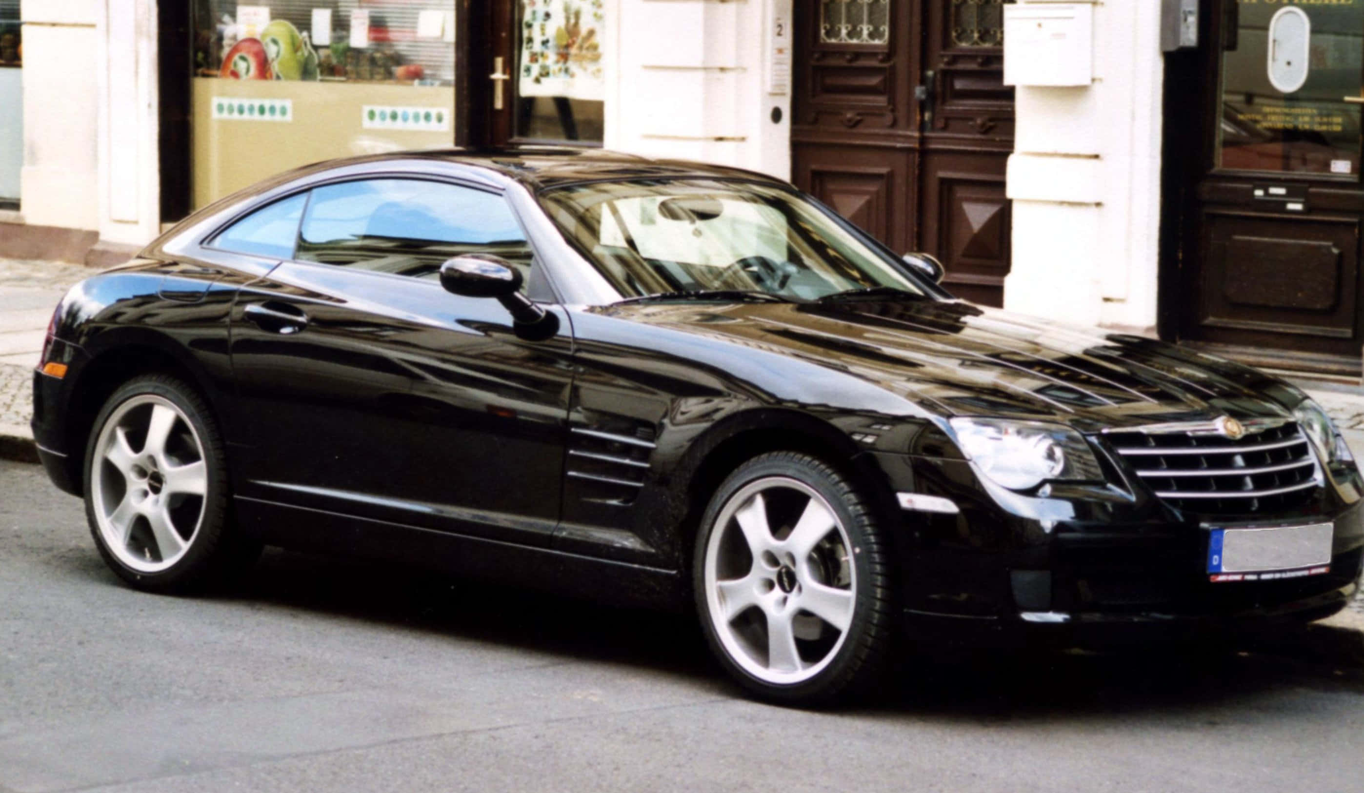 Chrysler Crossfire 桌布 壁紙 — 一輛時尚的黑色克萊斯勒Crossfire跑車停在城市街道上，配有反光車窗和銀色合金輪圈。