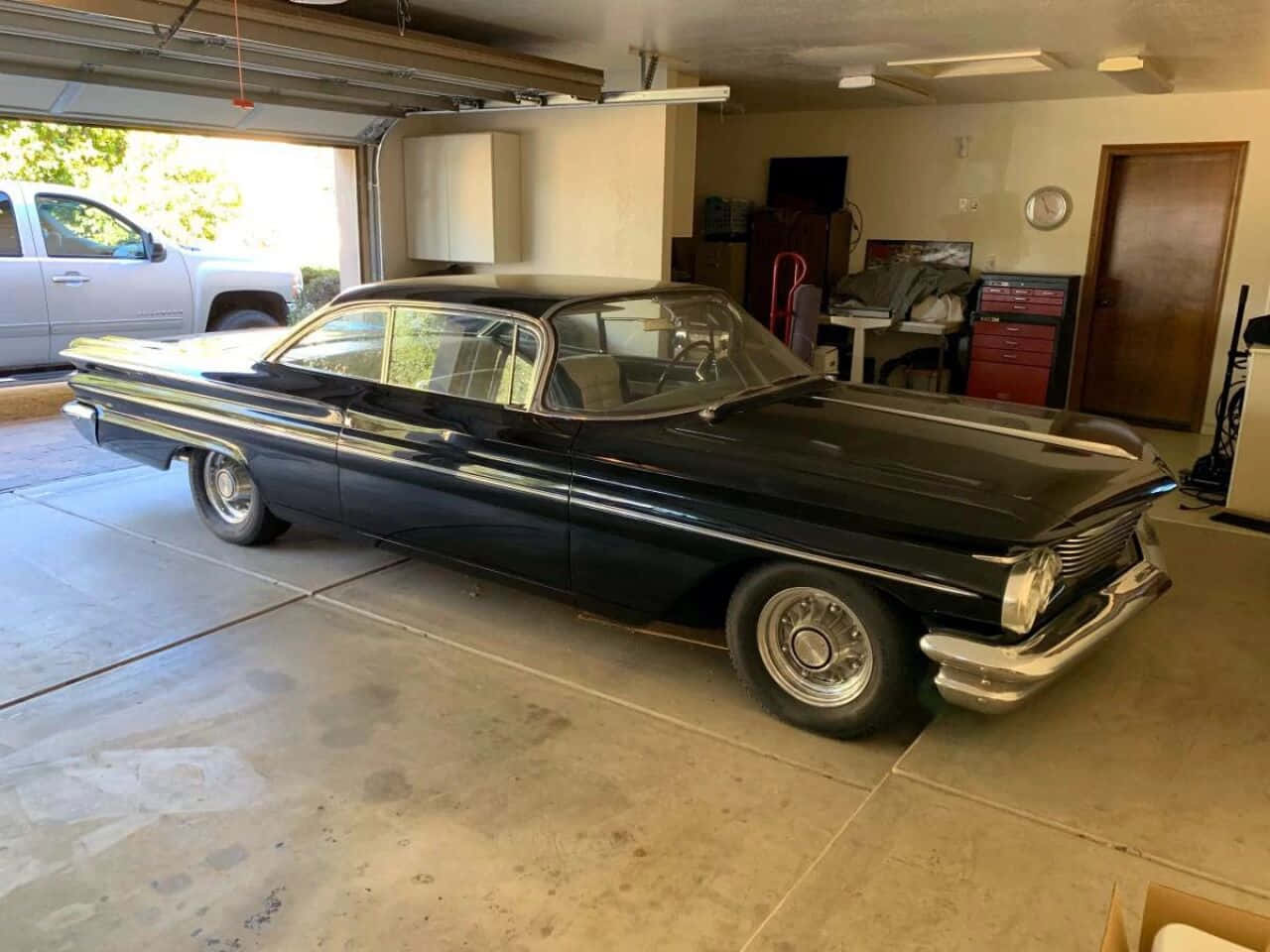 Pontiac Ventura 桌布 壁紙 — 一輛時尚的黑色經典汽車帶有鍍鉻裝飾，停放在光線充足的車庫內，外面可見一輛白色卡車。