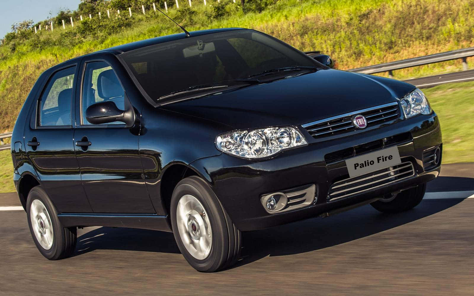 Fiat Palio 桌布 壁紙 — 一輛流線型黑色Fiat Palio Fire掀背車在陽光明媚的高速公路上奔馳，兩旁是翠綠的山丘。