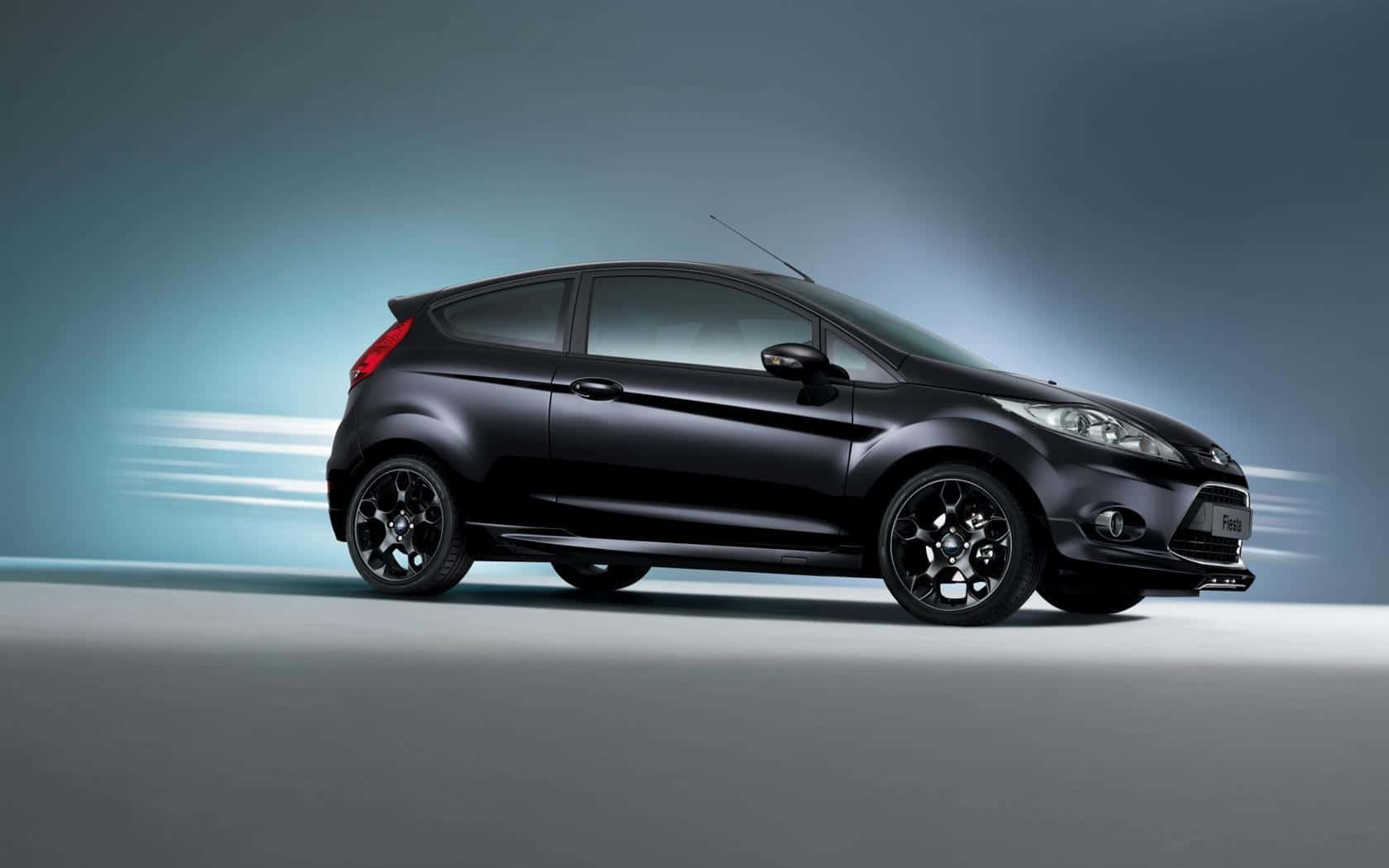 Ford Fiesta 桌布 壁紙 — 一輛時尚的黑色福特 Fiesta ST 在漸變藍灰色工作室背景前向前飛馳，帶有動態模糊條紋。