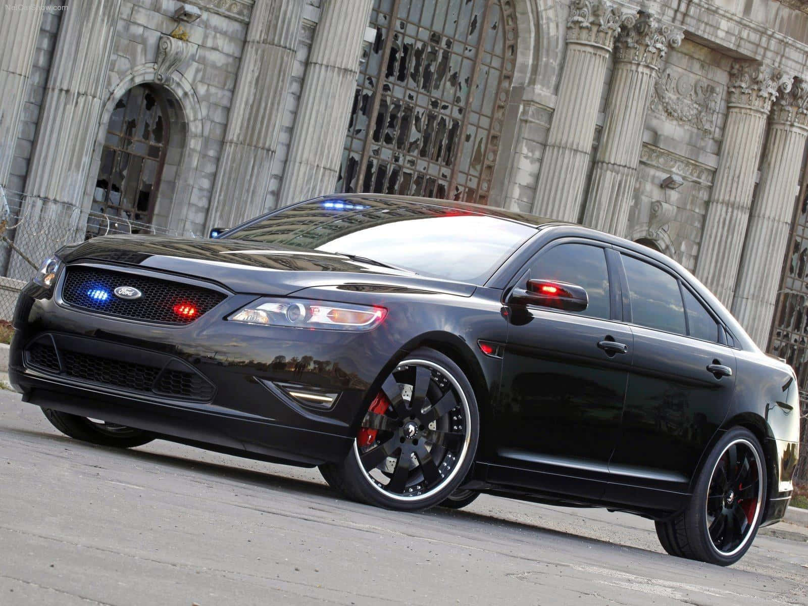 Ford Taurus 桌布 壁紙 — 一輛時尚的黑色福特警車，閃爍著警燈，停在一座宏偉的石建築前。