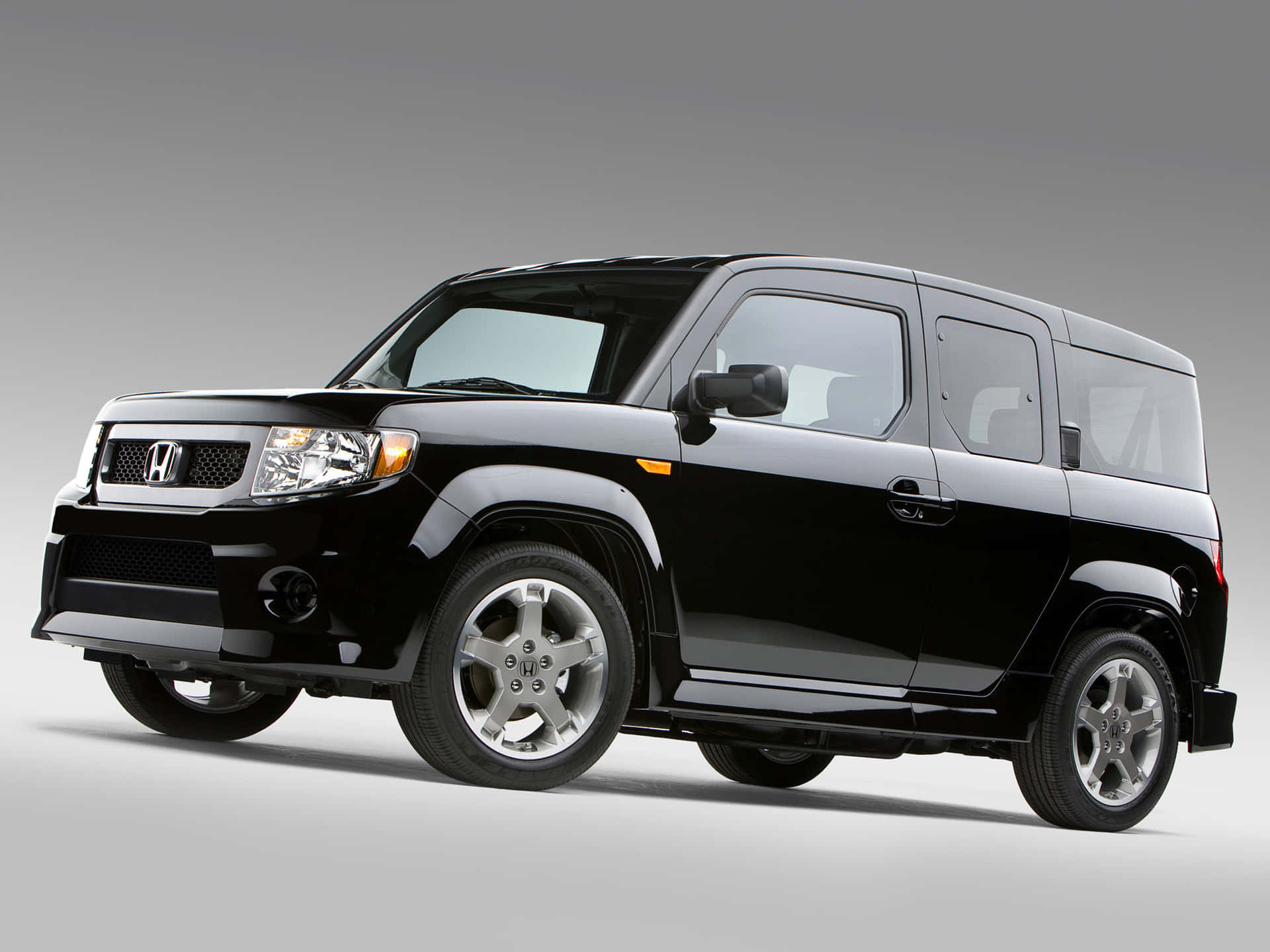 Honda Element 桌布 壁紙 — 一輛時尚的黑色本田Element SUV，在工作室燈光下搭配簡約灰色背景展示。