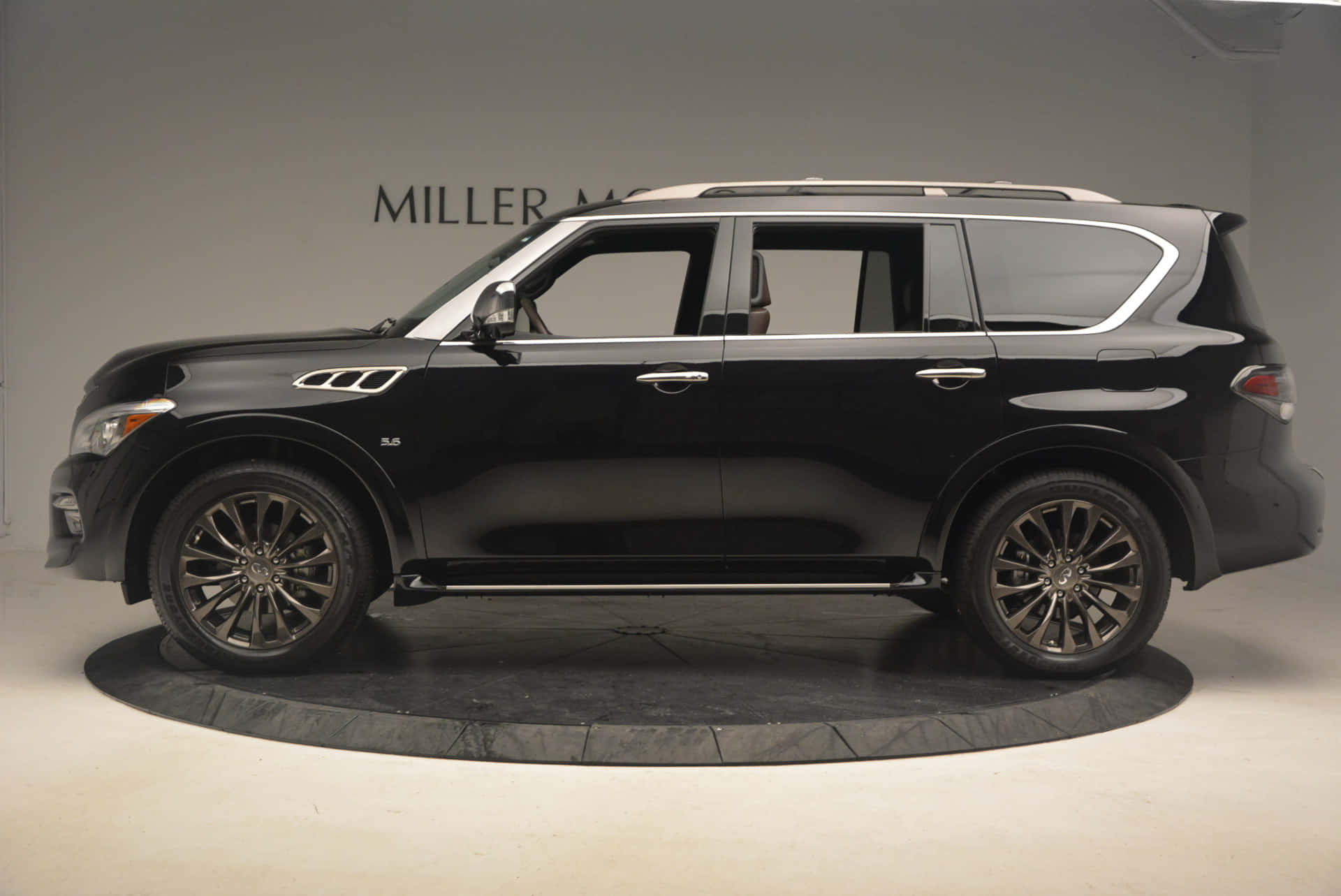 Infiniti Qx80 桌布 壁紙 — 一輛時尚的黑色Infiniti QX80 SUV在工作室環境中展示，背景為簡約灰色和圓形平台。