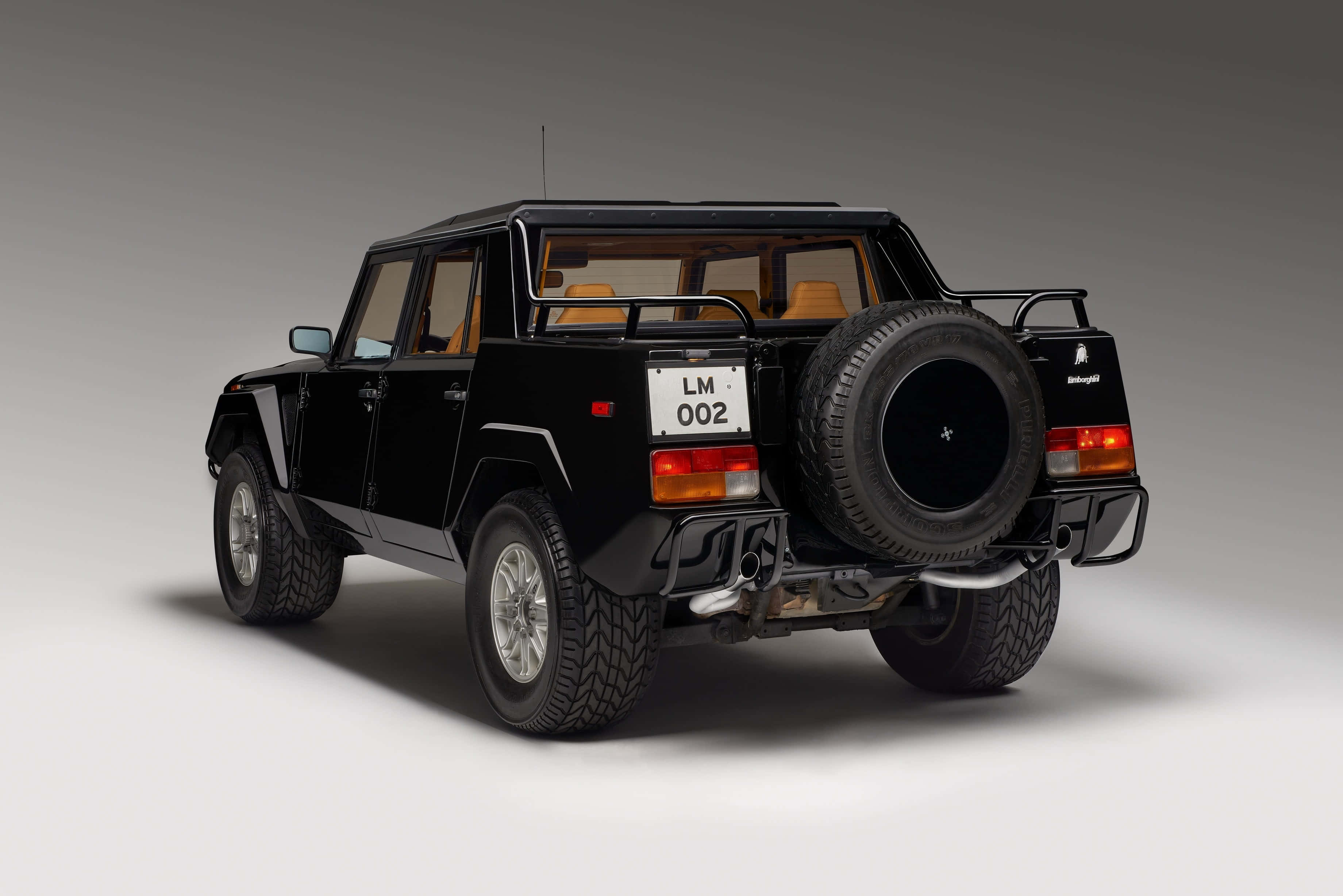 Lamborghini Lm002 桌布 壁紙 — 一輛時尚的黑色藍寶堅尼LM002豪華越野車，從後方四分之三角度拍攝，背景為中性攝影棚。