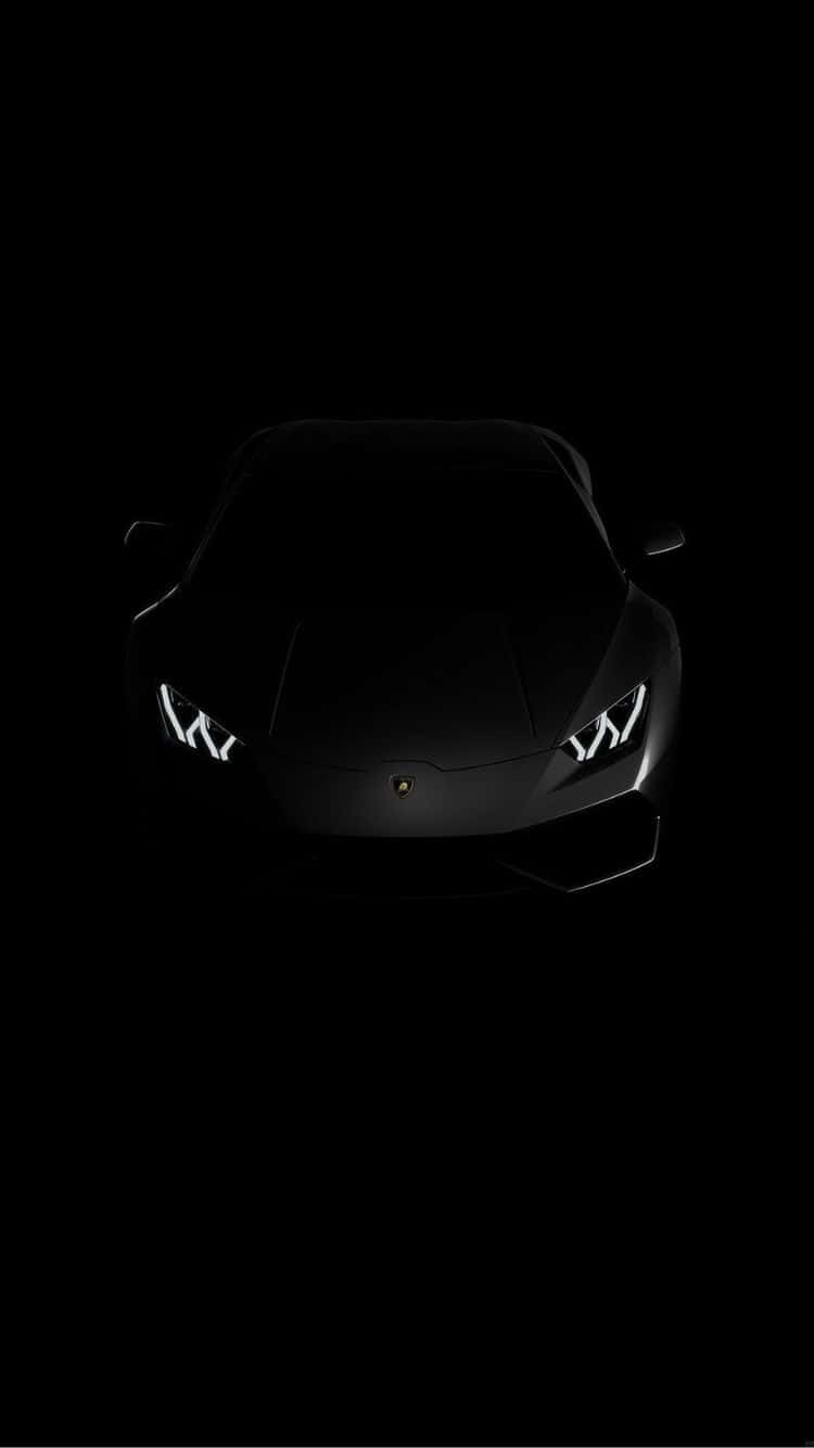 黑色藍寶堅尼跑車在黑暗中亮著車頭燈。 — iPhone 11 Pro Max 壁紙