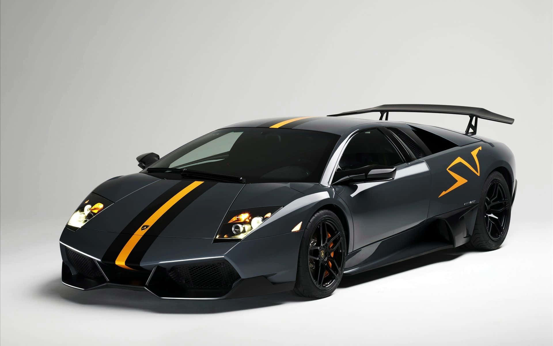 Lamborghini Murciélago 桌布 壁紙 — 一架時尚的黑色藍寶堅尼，帶有醒目的黃色條紋和大型尾翼，在簡約的灰色工作室背景前蓄勢待發。