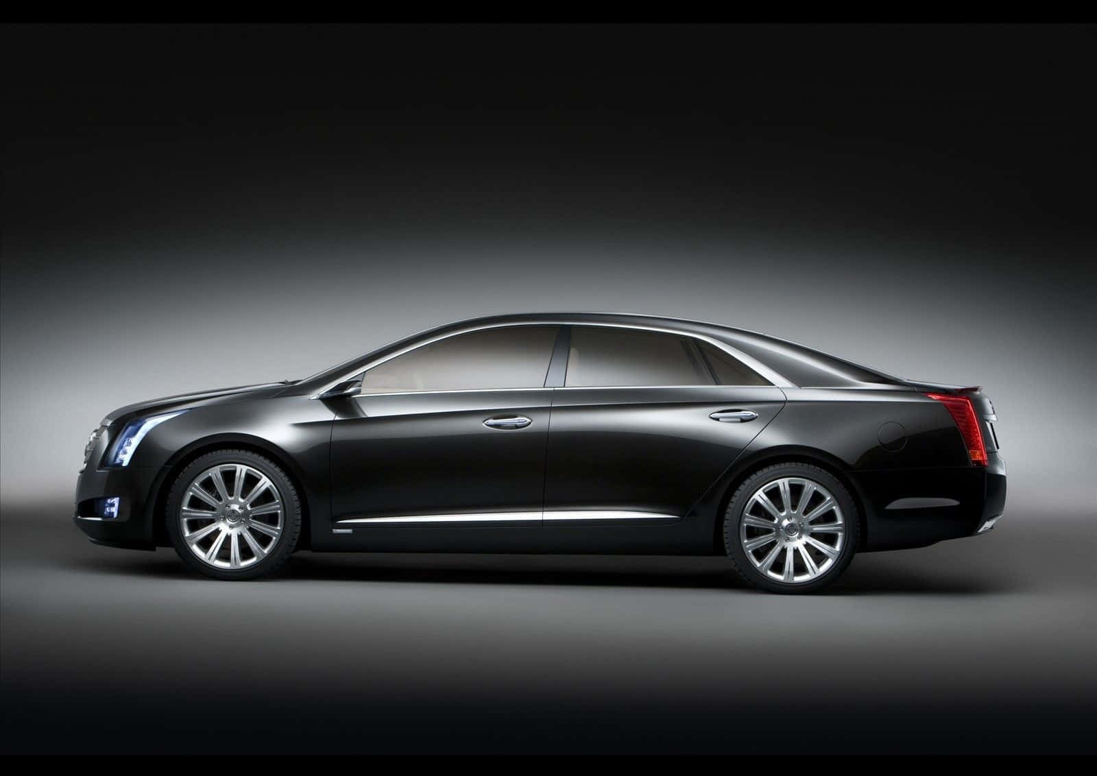 Cadillac Xts 桌布 壁紙 — 一輛時尚黑色豪華轎車在側面展示，背景為帶有戲劇性照明的深色漸變工作室背景。