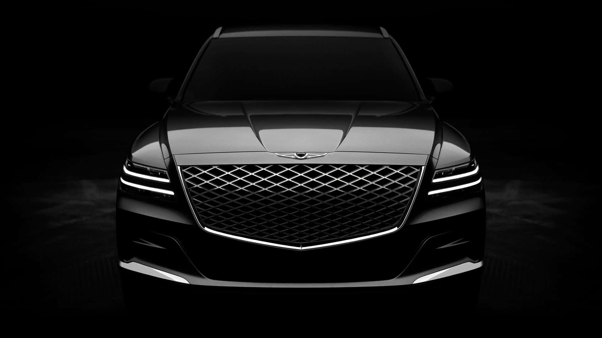 Genesis G80 桌布 壁紙 — 一輛時尚黑色豪華SUV的正面視圖，在黑暗的攝影棚背景下被銳利的LED頭燈照亮。