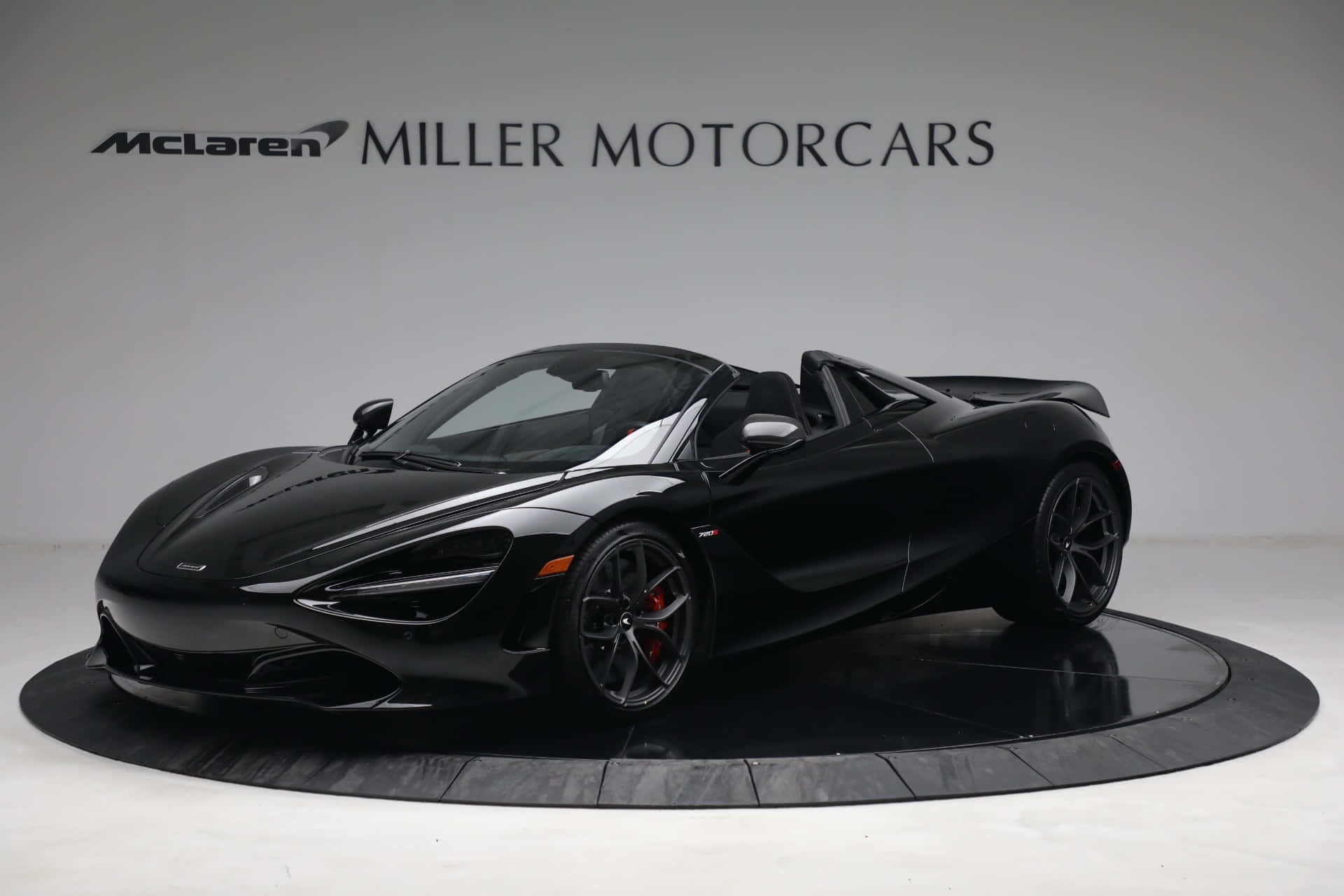 Mclaren 720s Spider 桌布 壁紙 — 一輛流線型黑色McLaren 720S Spider敞篷跑車在圓形展示台上於攝影棚燈光下閃閃發光。