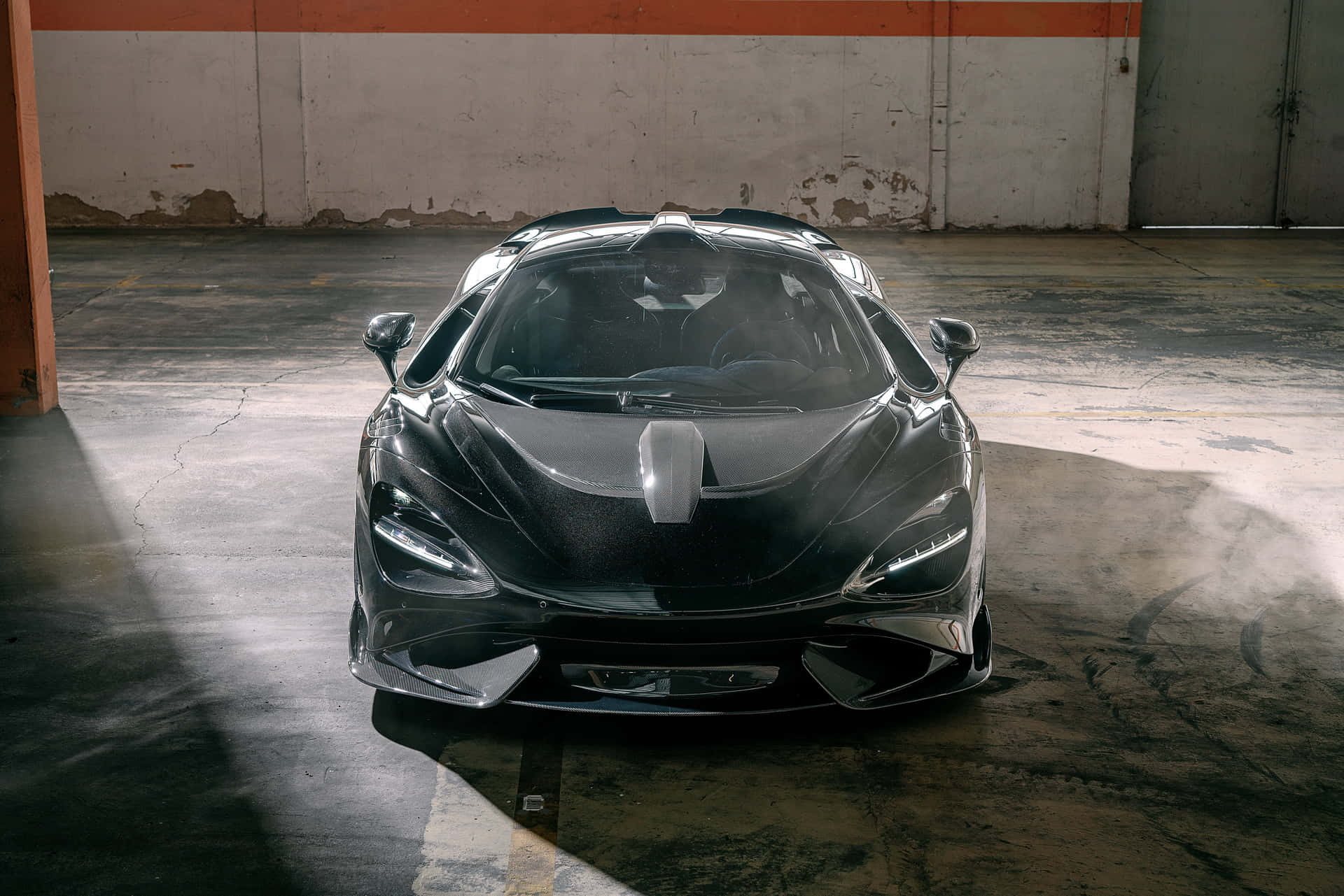 Mclaren 765lt 桌布 壁紙 — 一架時尚的黑色McLaren跑車在骯髒的工業車庫中，在戲劇性燈光下閃閃發光。