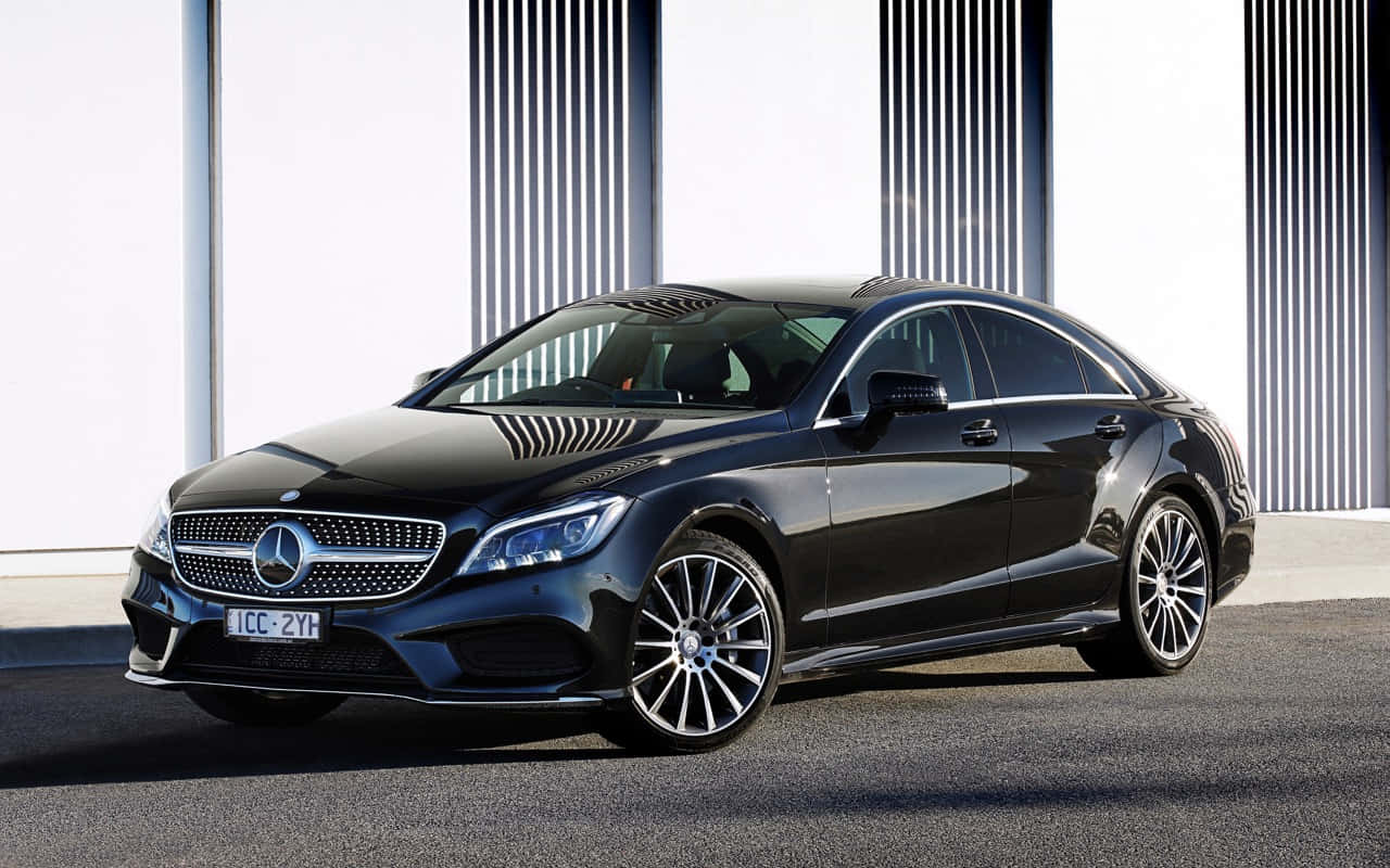 Mercedes Benz Cls-class 桌布 壁紙 — 一輛時尚的黑色賓士CLS轎車在明亮的日光下，以現代白色和灰色垂直板條牆為背景閃閃發光。