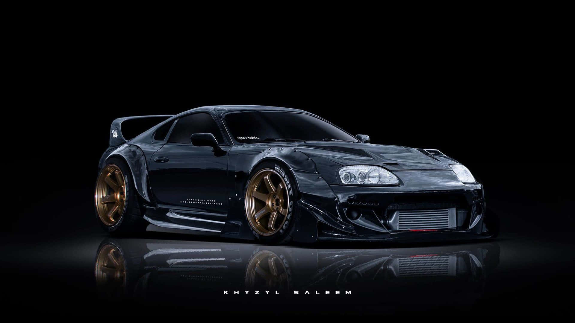 黑色改裝跑車配金色輪圈，在黑暗工作室的反光地板上。 — Toyota Supra 壁紙