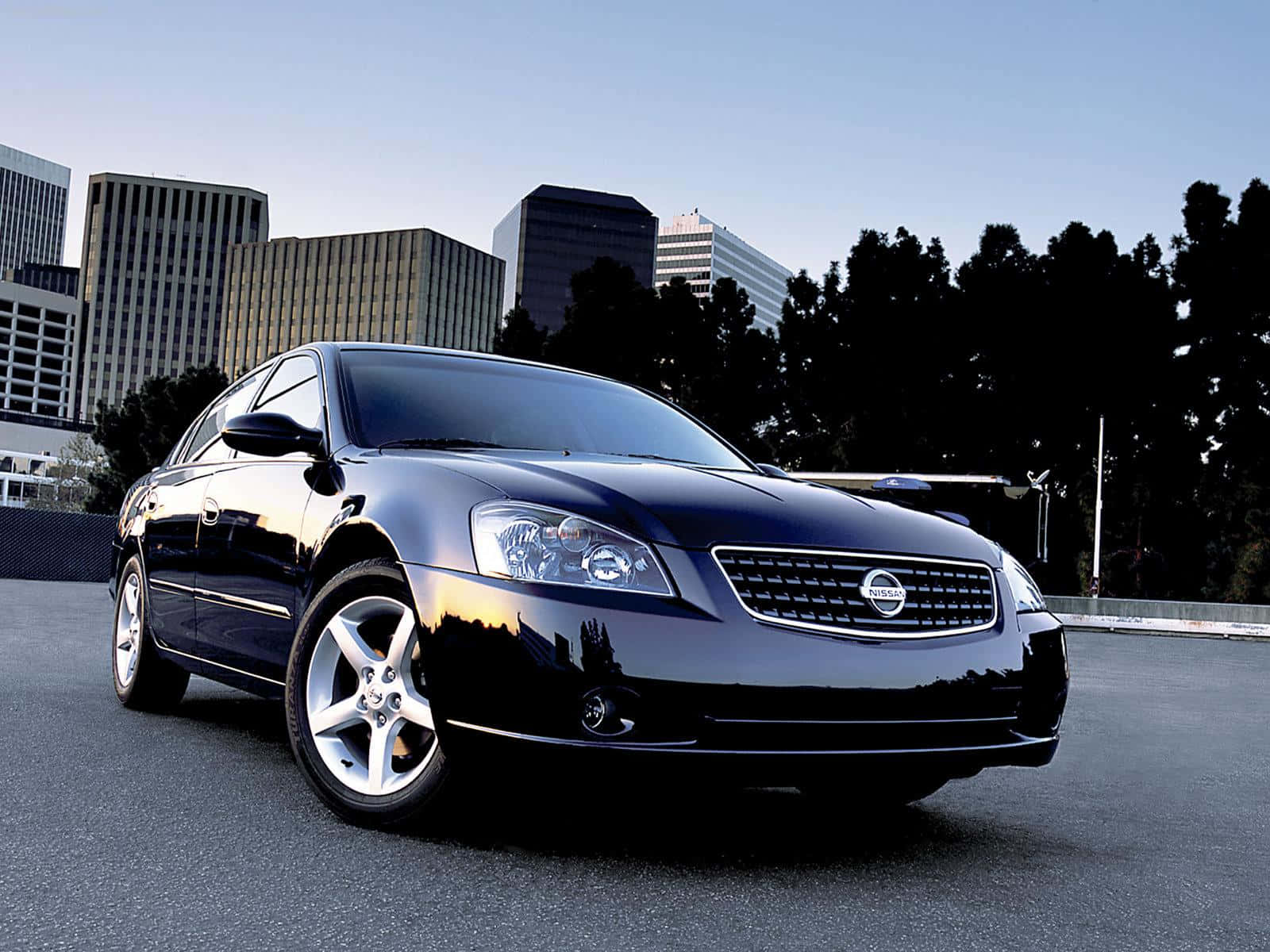 Nissan Altima 桌布 壁紙 — 一輛時尚的黑色日產轎車在暮色天空下閃耀，背景是城市天際線和樹木。