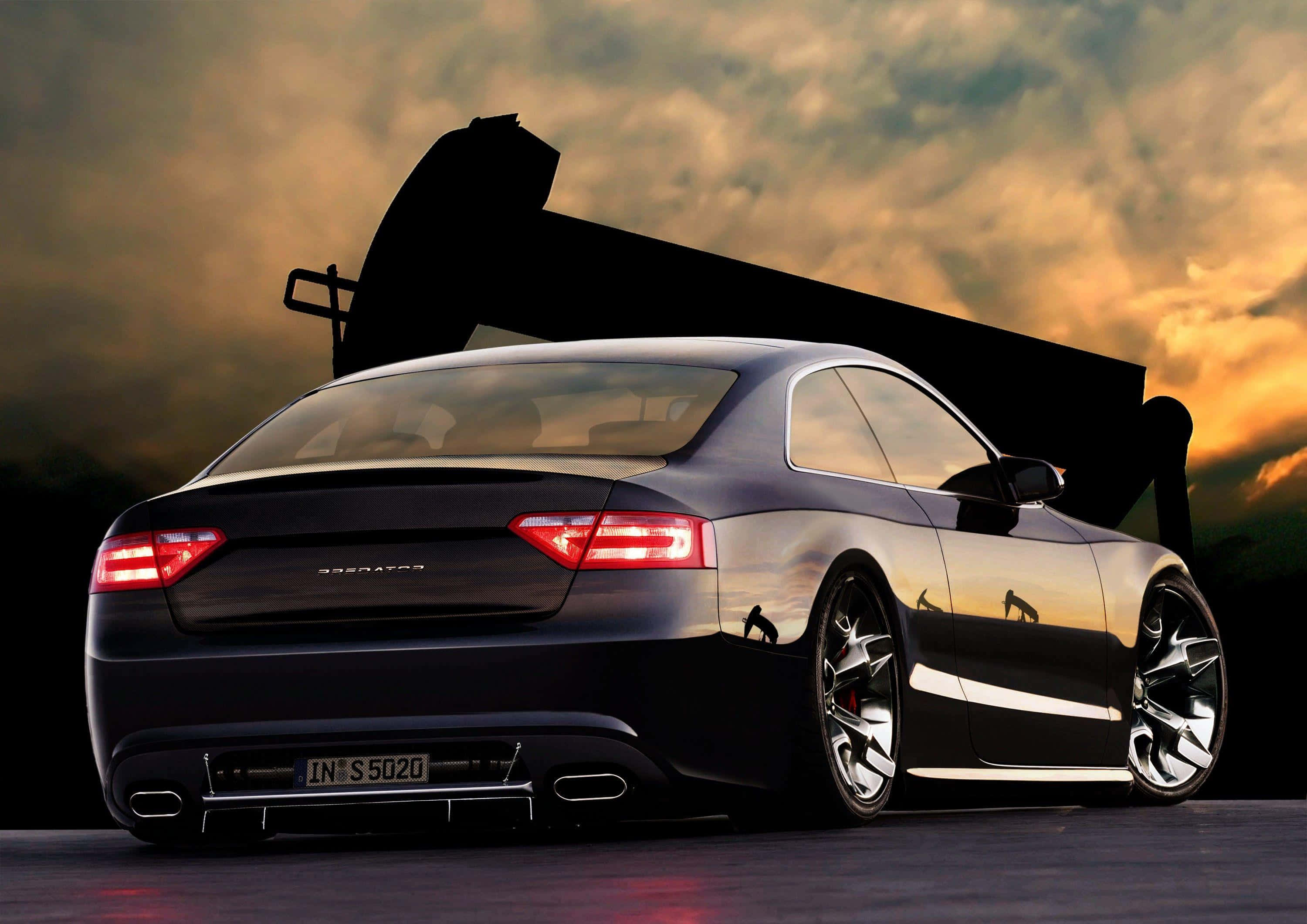 Audi S5 桌布 壁紙 — 一輛時尚的黑色跑車，帶有發光的紅色尾燈，在戲劇性的日落天空下，背後有一個巨大的黑色翅膀剪影。