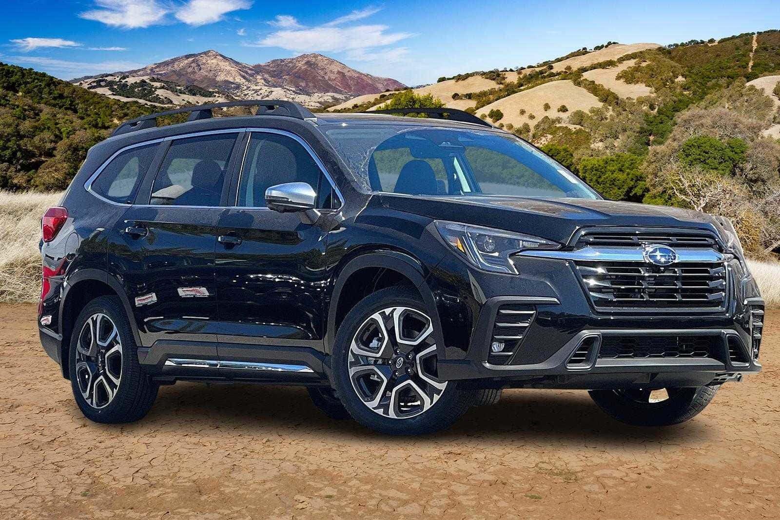Subaru Ascent 桌布 壁紙 — 一輛時尚的黑色 Subaru SUV 停泊在龜裂的土地上，背景是起伏的丘陵和遠處的山脈，天空湛藍明亮。