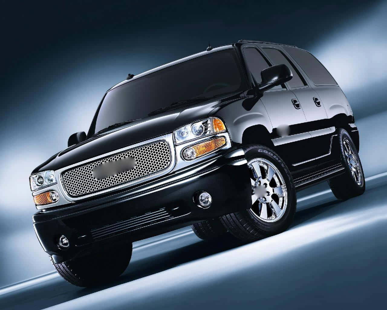 Gmc Yukon 桌布 壁紙 — 一輛時尚的黑色SUV，帶有鍍鉻裝飾和定制輪圈，在漸變藍色工作室背景前動態傾斜。