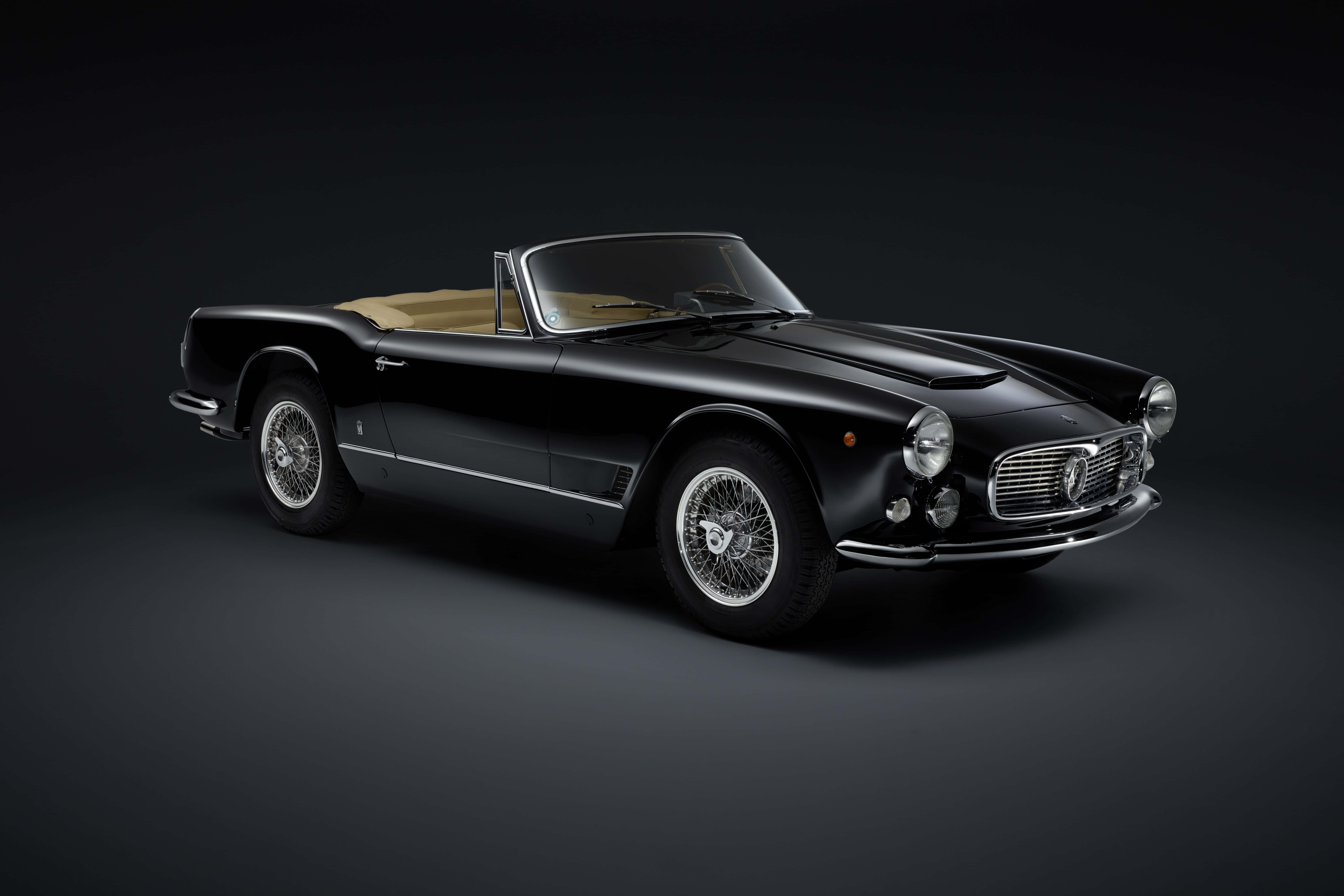 Maserati 3500 Gt 桌布 壁紙 — 一輛時尚的黑色復古法拉利敞篷車，配備米色內裝，在攝影棚燈光下於深色漸變背景中閃耀。
