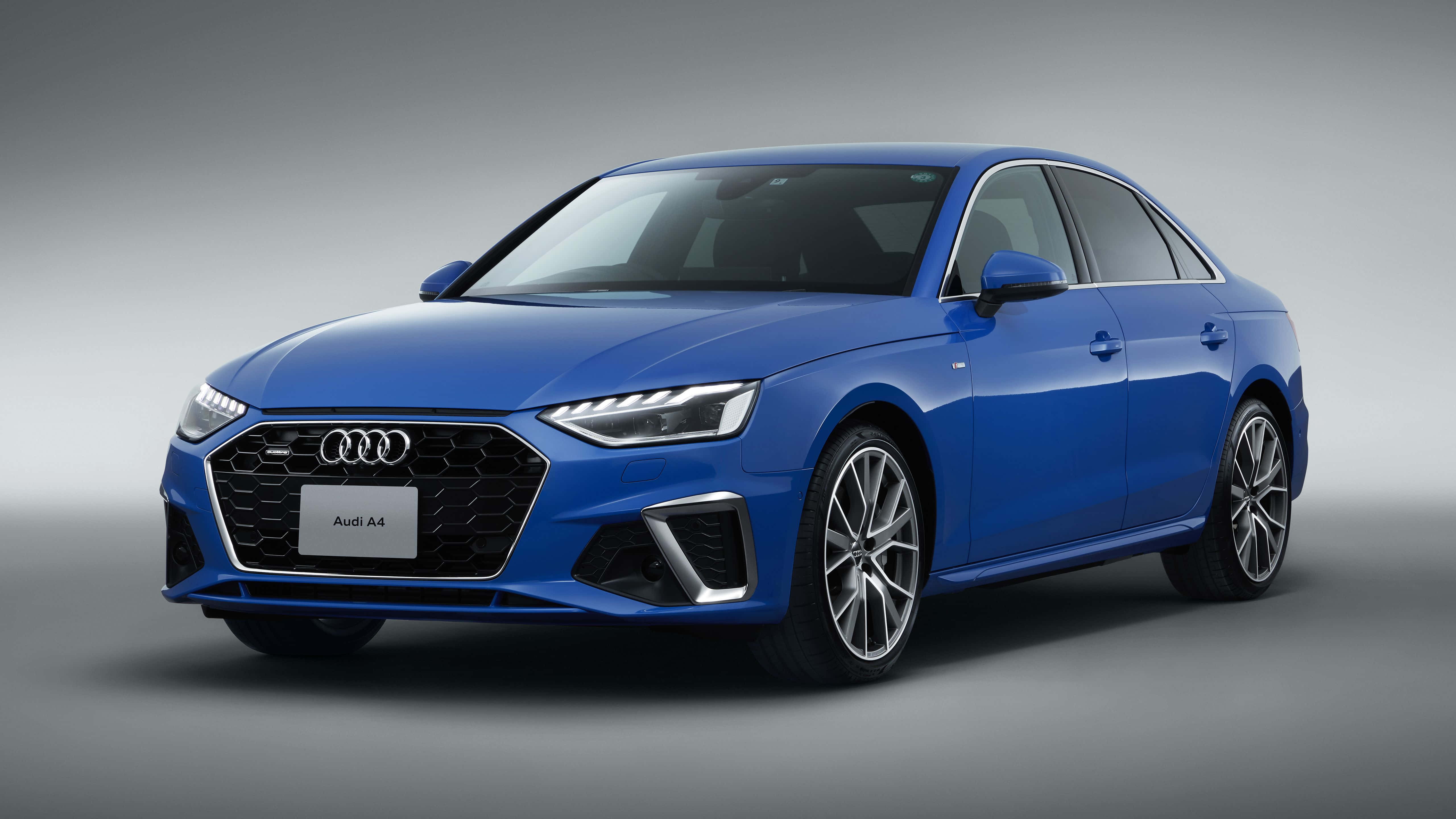 Audi A4 桌布 壁紙 — 一輛時尚的藍色奧迪A4轎車在攝影棚燈光下閃閃發光，背景為中性灰色。