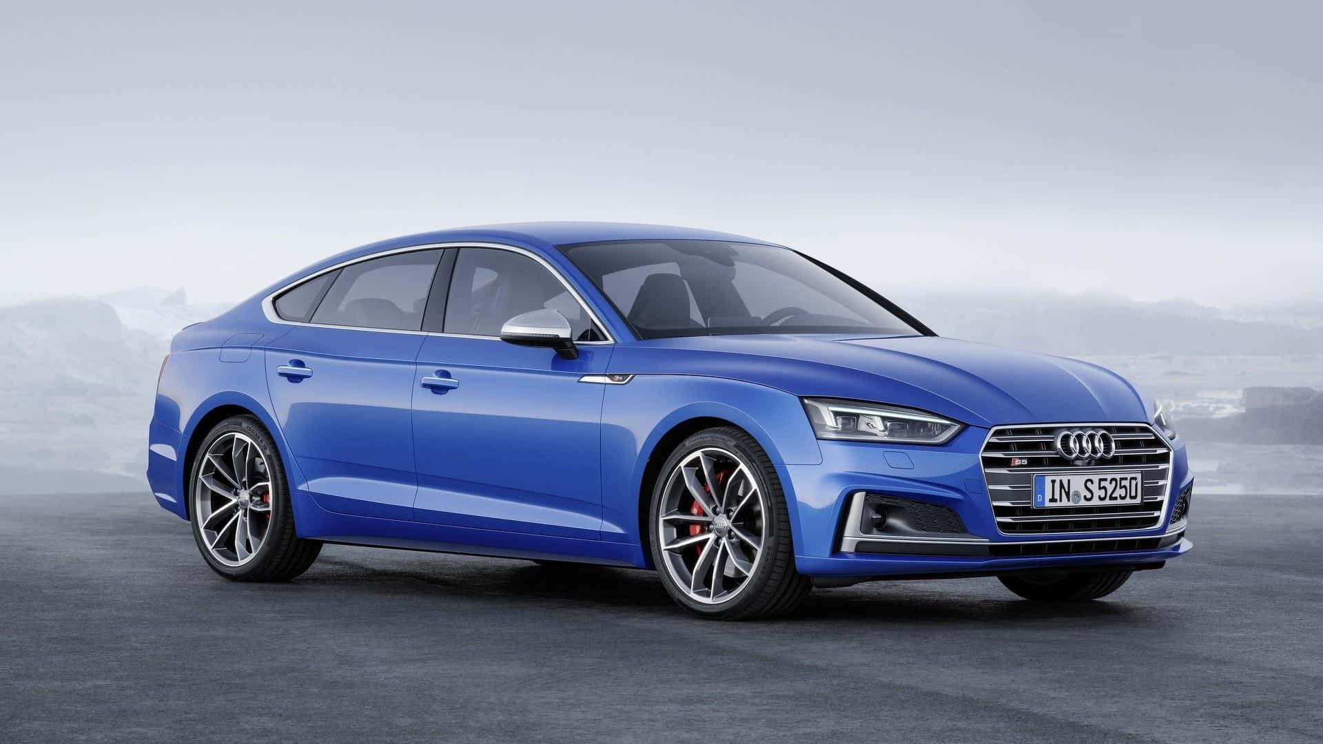 Audi A5 桌布 壁紙 — 一台時尚的藍色奧迪S5轎車在柔和日光下閃耀，背景是霧氣繚繞的山巒。