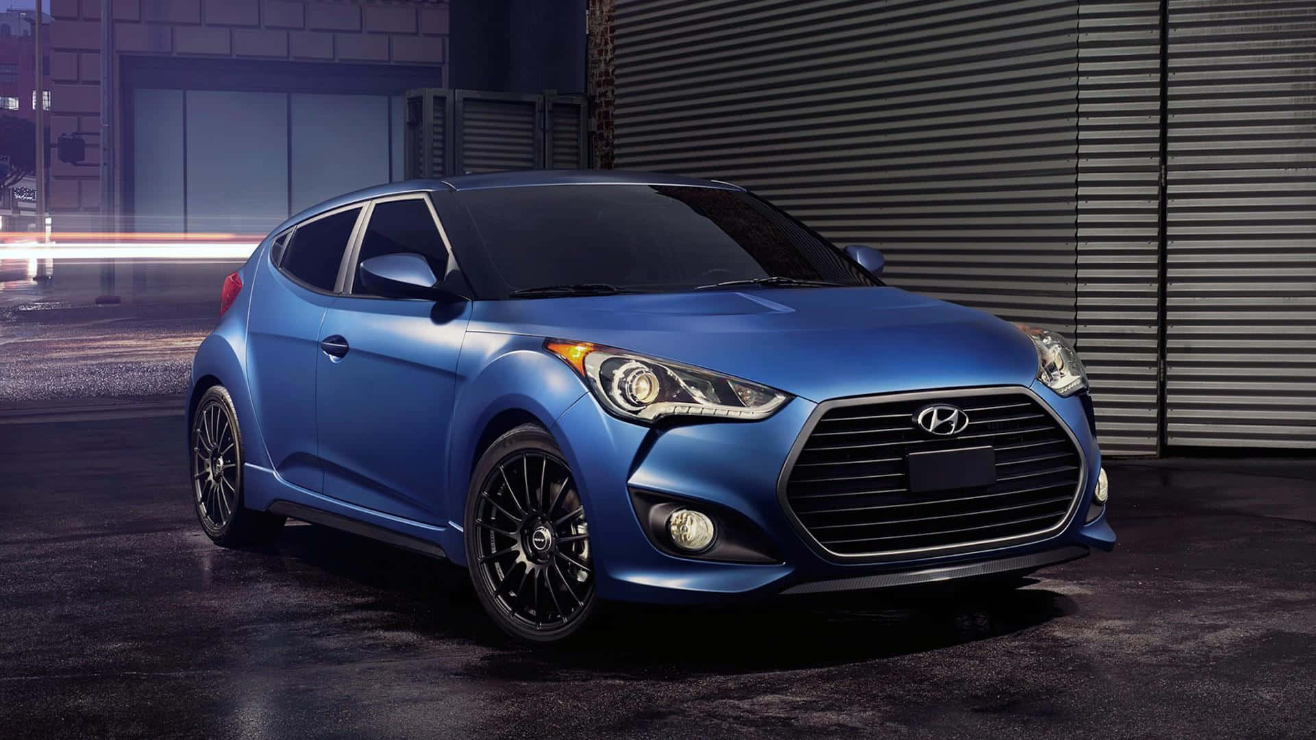 Hyundai Veloster 桌布 壁紙 — 一輛時尚的藍色現代Veloster跑車在城市的燈光下，靠著波紋金屬牆閃閃發光。
