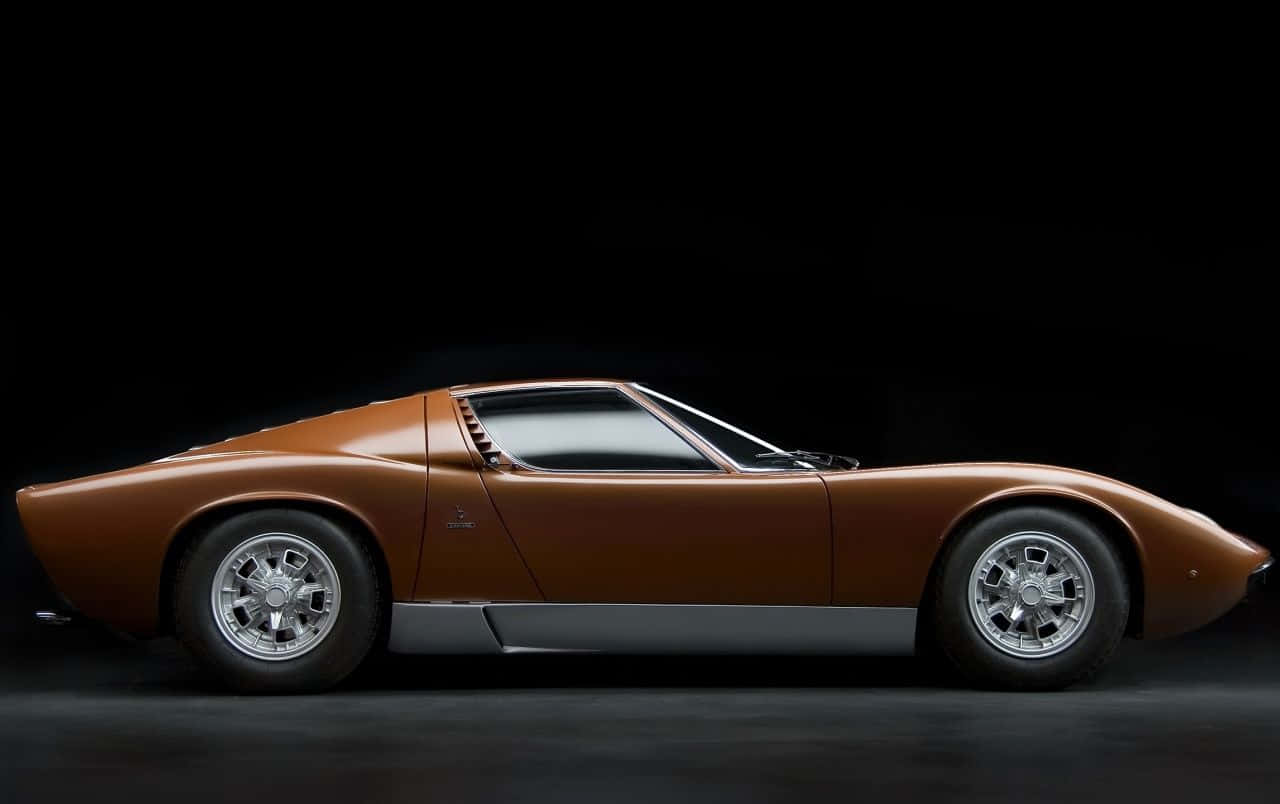 Lamborghini Miura 桌布 壁紙 — 一輛流線型青銅色藍寶堅尼Miura跑車，以側面輪廓展示在黑色攝影棚背景前。