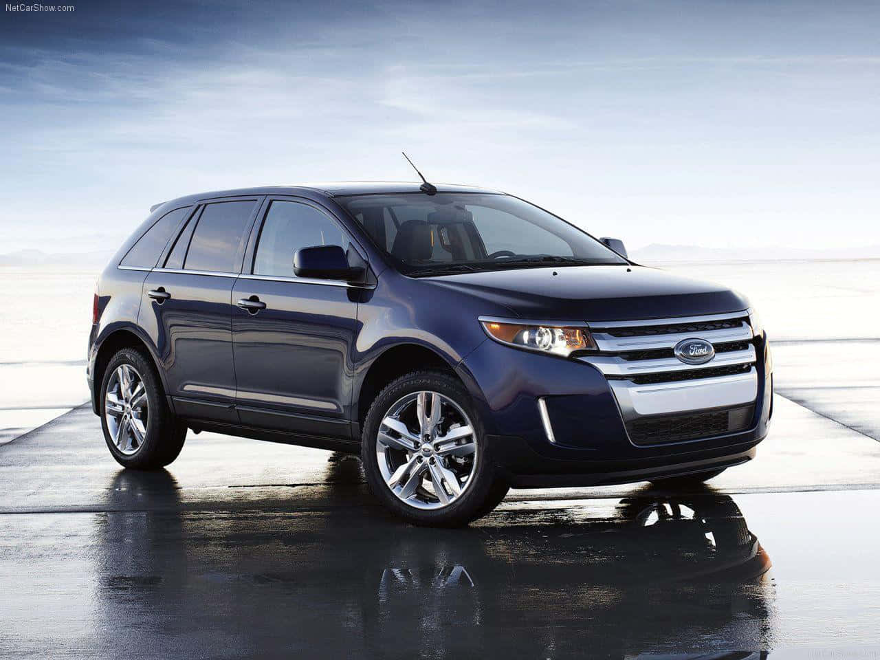 Ford Edge 桌布 壁紙 — 一輛時尚的深藍色福特Edge SUV在柔和的暮色天空下，停在潮濕的反光表面上。