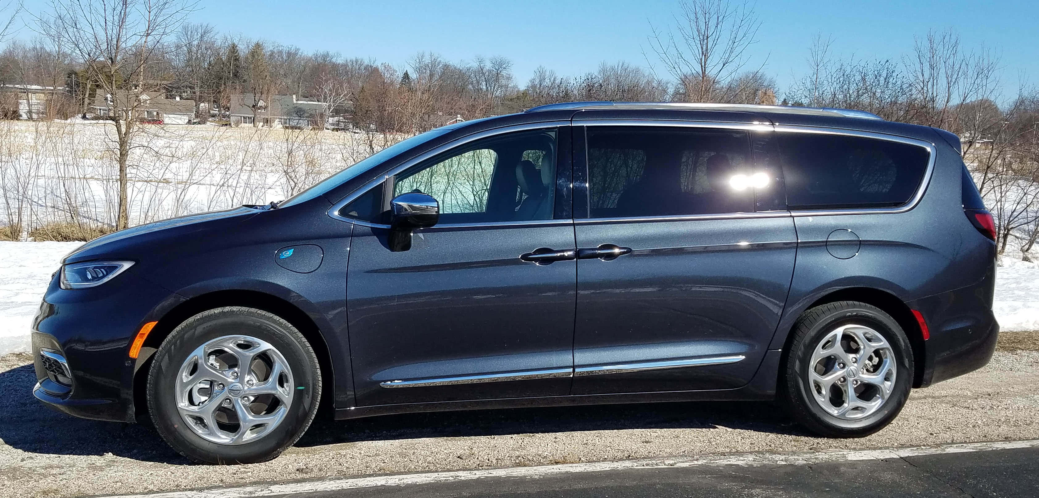 Chrysler Pacifica 桌布 壁紙 — 一輛時尚深藍色小型貨車停泊在碎石路上，旁邊是白雪覆蓋的田野，上方是晴朗的藍天。