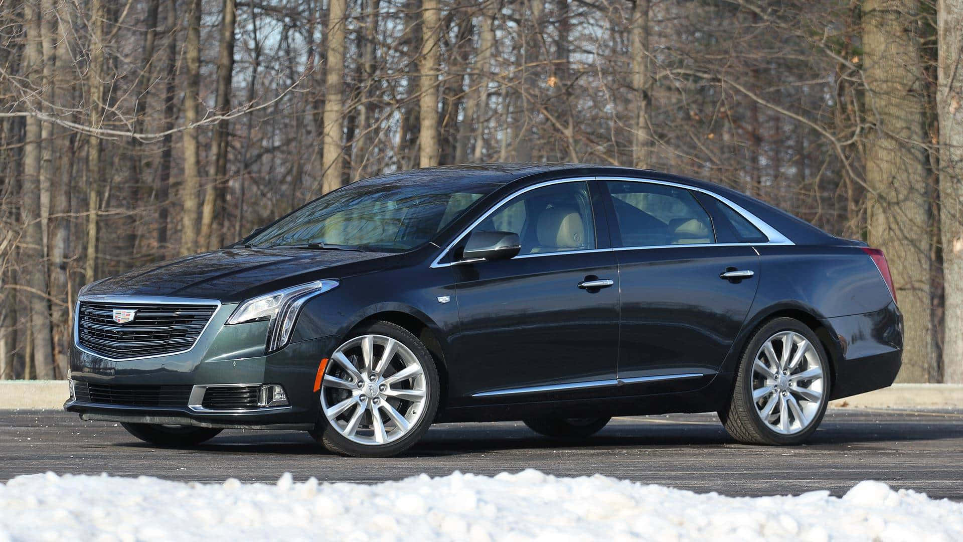Cadillac Xts 桌布 壁紙 — 一輛時尚的深灰色 Cadillac CT6 轎車停在雪地路邊，背景有光禿禿的樹木。