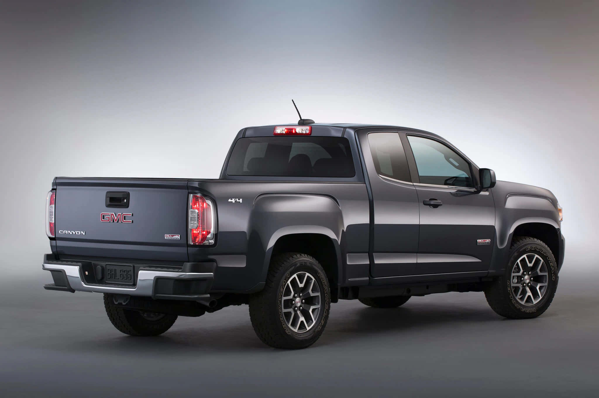 Gmc Canyon 桌布 壁紙 — 一輛時尚的深灰色GMC Canyon皮卡車在工作室環境中展示，背景為漸變灰色。