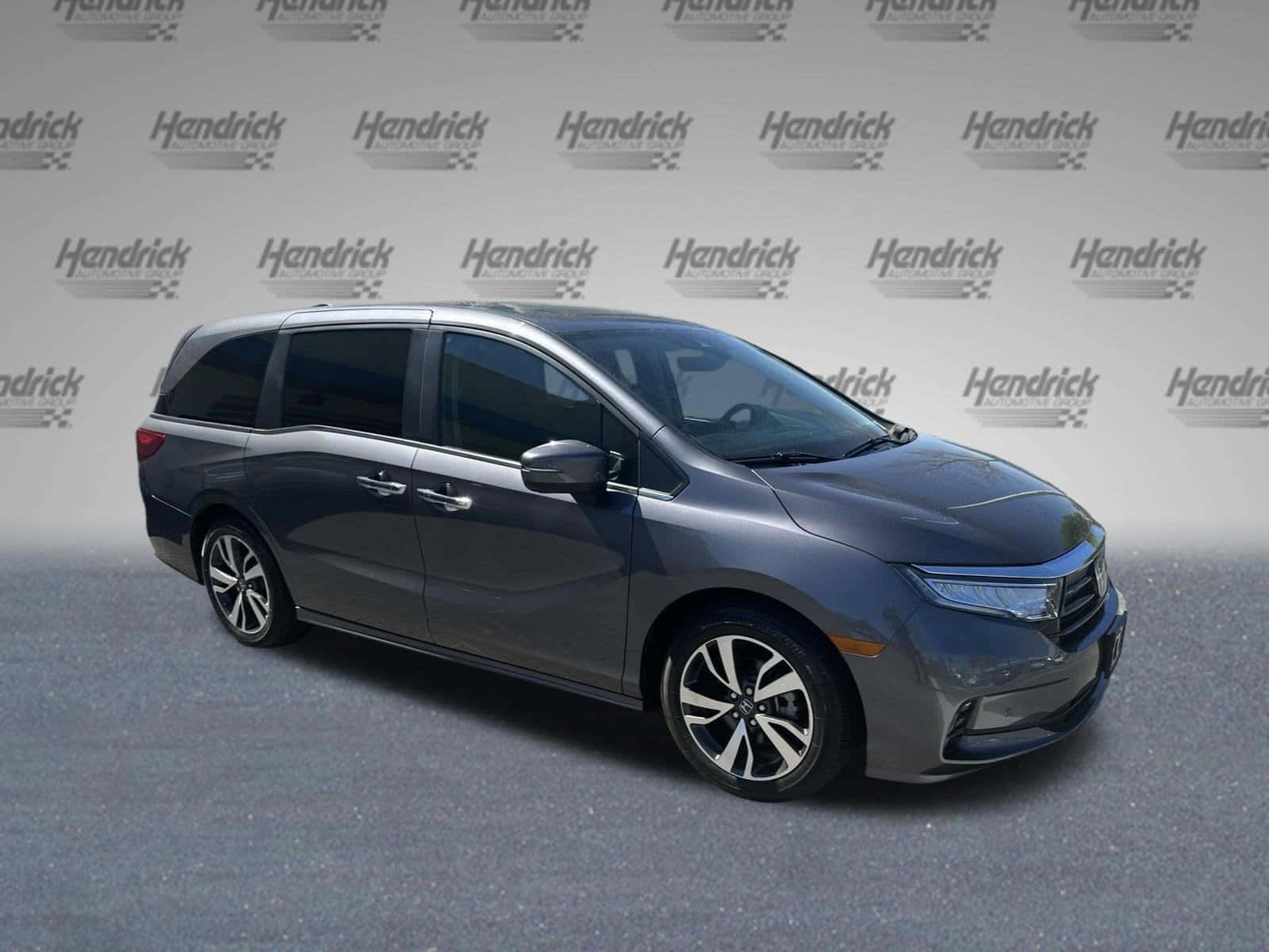 Honda Odyssey 桌布 壁紙 — 一輛時尚的深灰色本田奧德賽小型貨車在工作室環境中展示，帶有品牌背景。