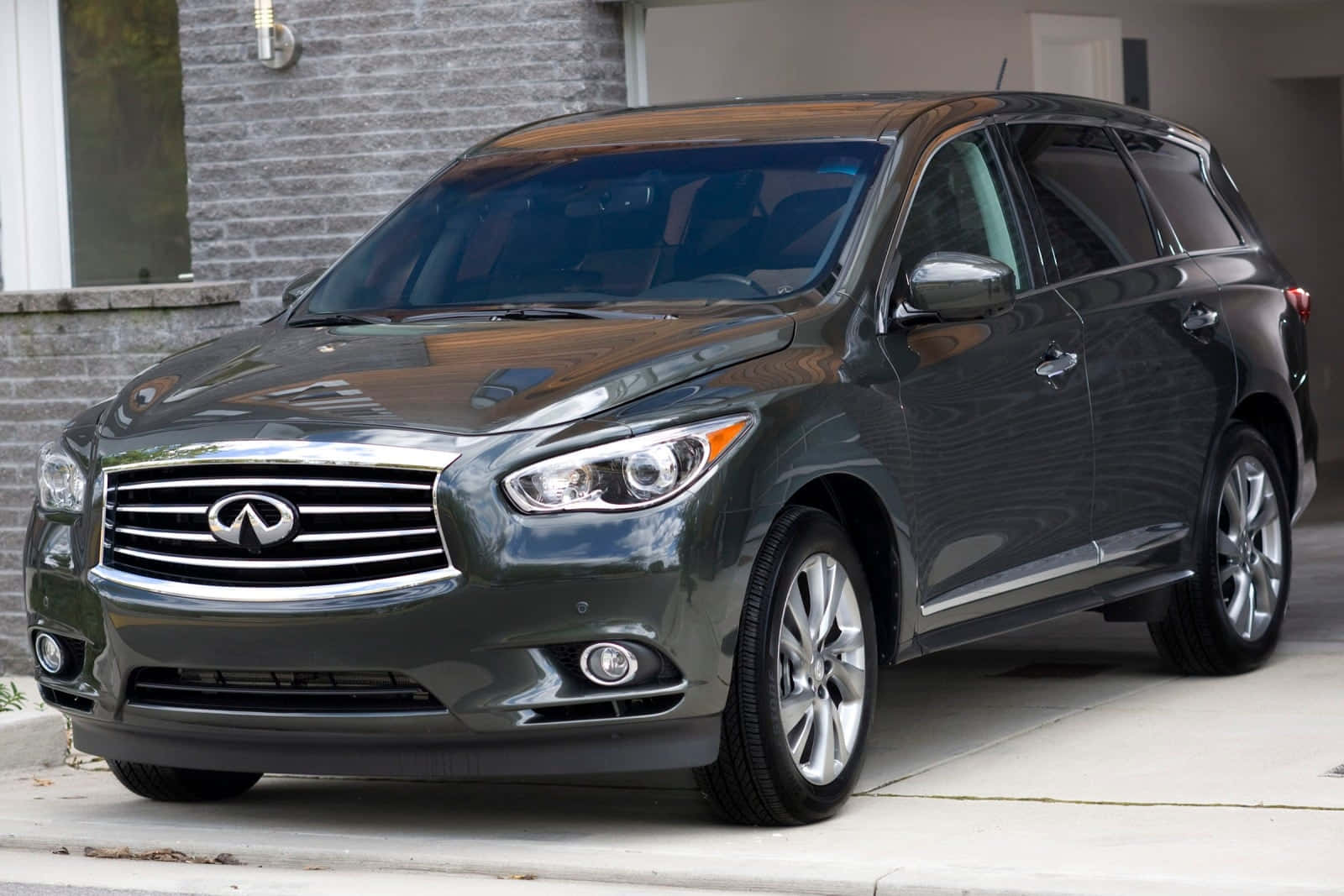 Infiniti Jx35 桌布 壁紙 — 一輛時尚的深灰色 Infiniti QX60 SUV 停放在磚房旁邊的混凝土車道上，磚房擁有現代化外觀。