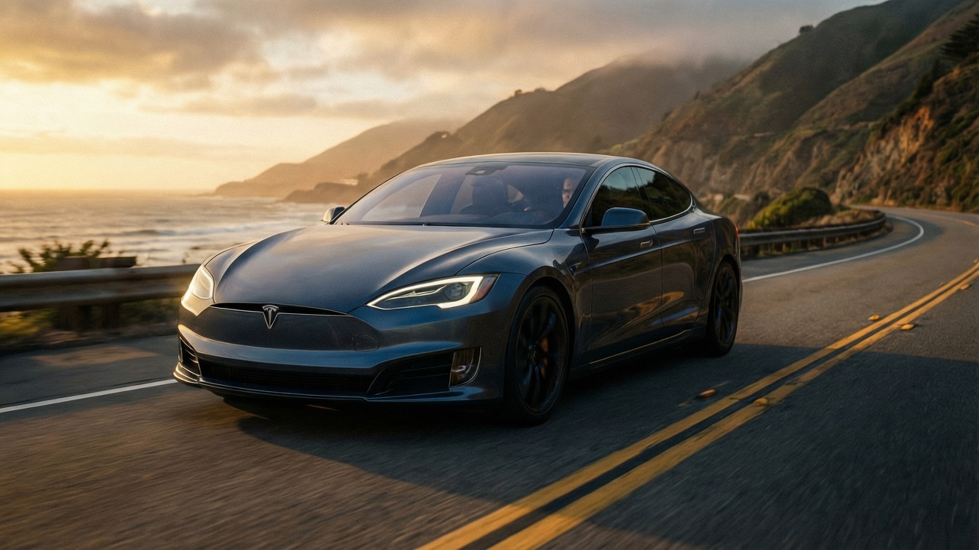 Coastal Highway Golden Hour 壁紙 — 一架時尚的深灰色Tesla Model S在黃金時段沿著海岸公路行駛，背景是海洋懸崖。