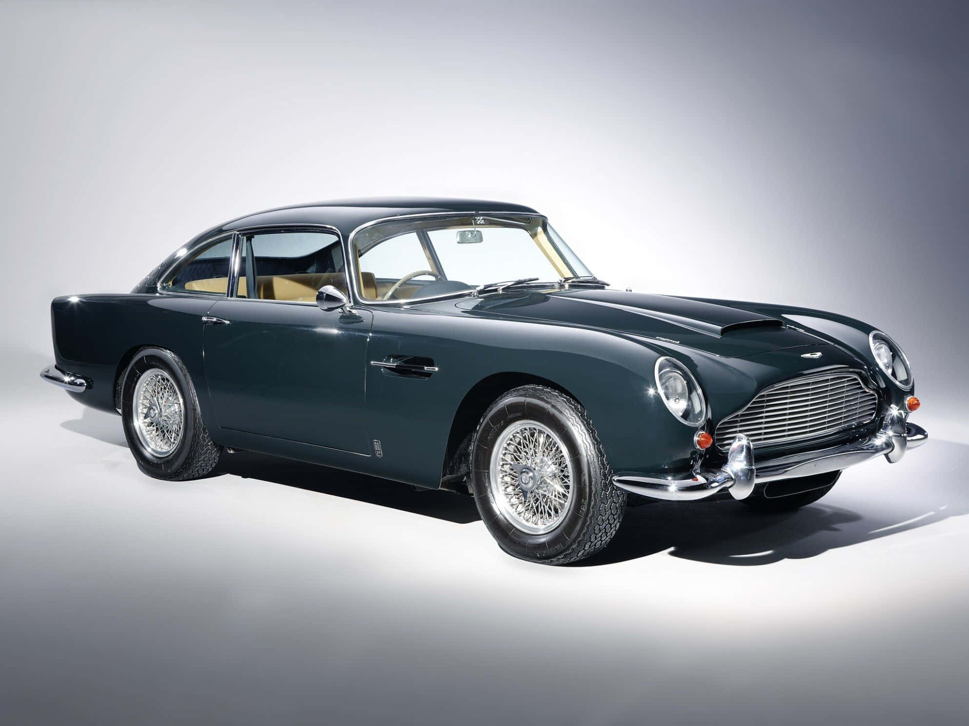 Aston Martin Db5 桌布 壁紙 — 一輛時尚的深綠色經典 Aston Martin DB5 在攝影棚燈光下閃耀，背景為簡約灰色。