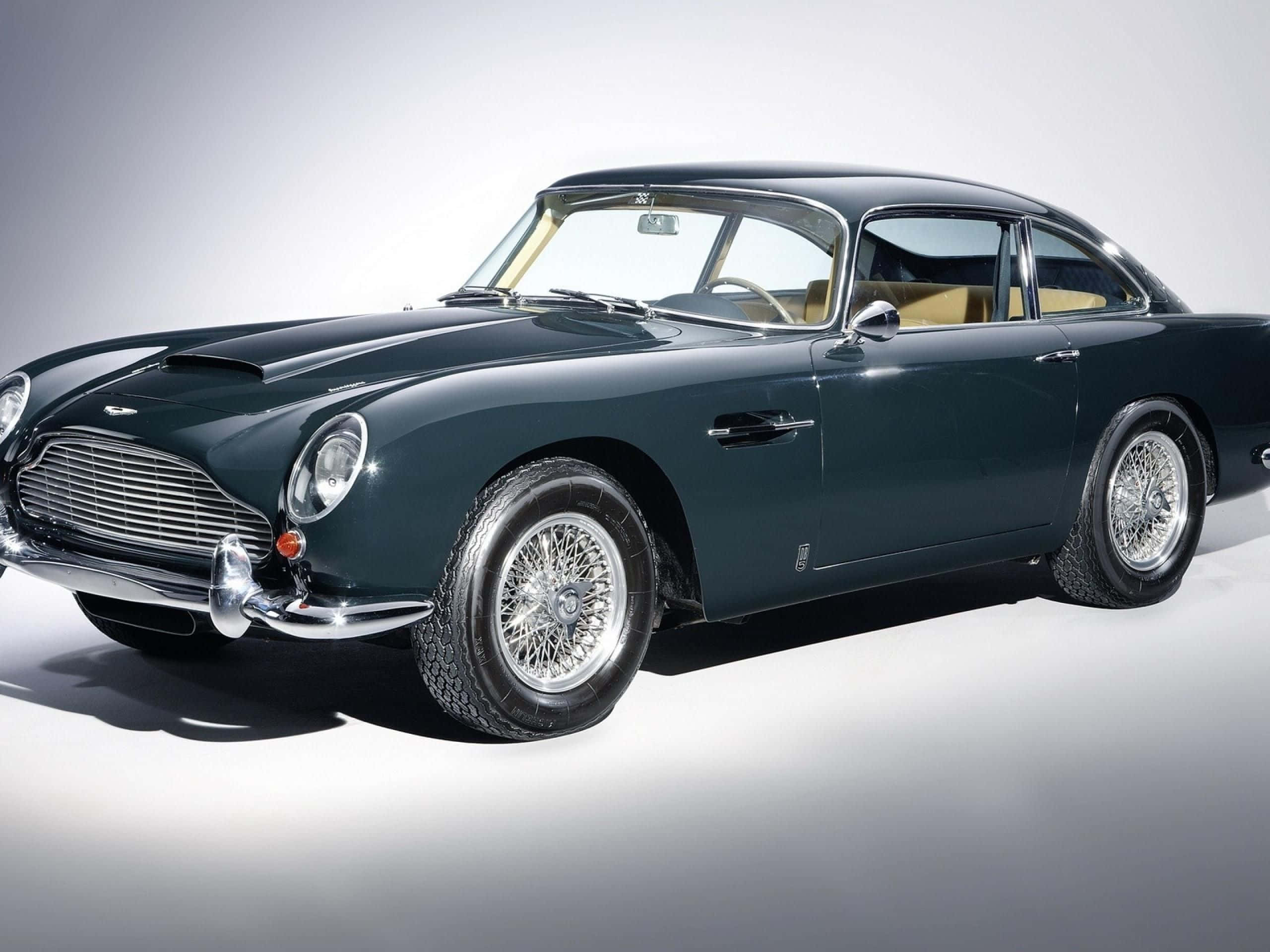 Aston Martin Db5 桌布 壁紙 — 一輛時尚的深綠色經典 Aston Martin DB5 在工作室燈光下閃閃發光，背景是簡約的白色。