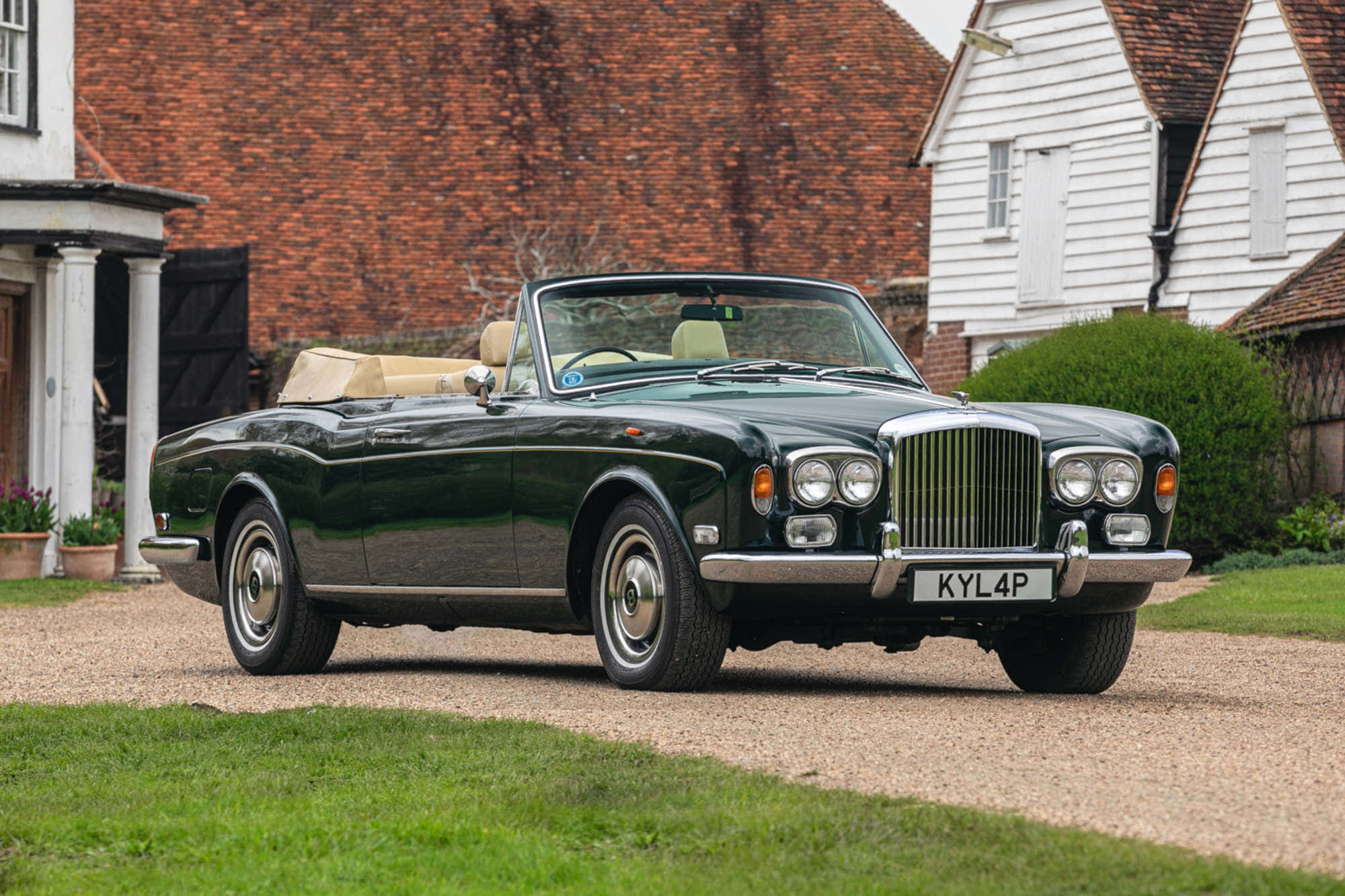 Bentley T1 桌布 壁紙 — 一架時尚的深綠色經典賓利敞篷車停泊在碎石車道上，旁邊是傳統英式小屋，紅磚白木牆身。