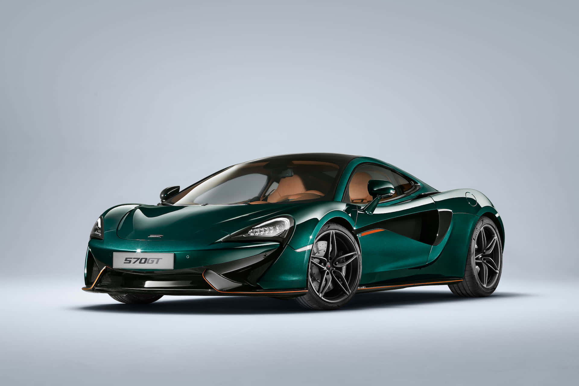 Mclaren Gt 桌布 壁紙 — 一台時尚的翡翠綠色McLaren 570GT跑車，帶有黑色飾邊和米色內飾，擺放在極簡的淺灰色工作室背景前。