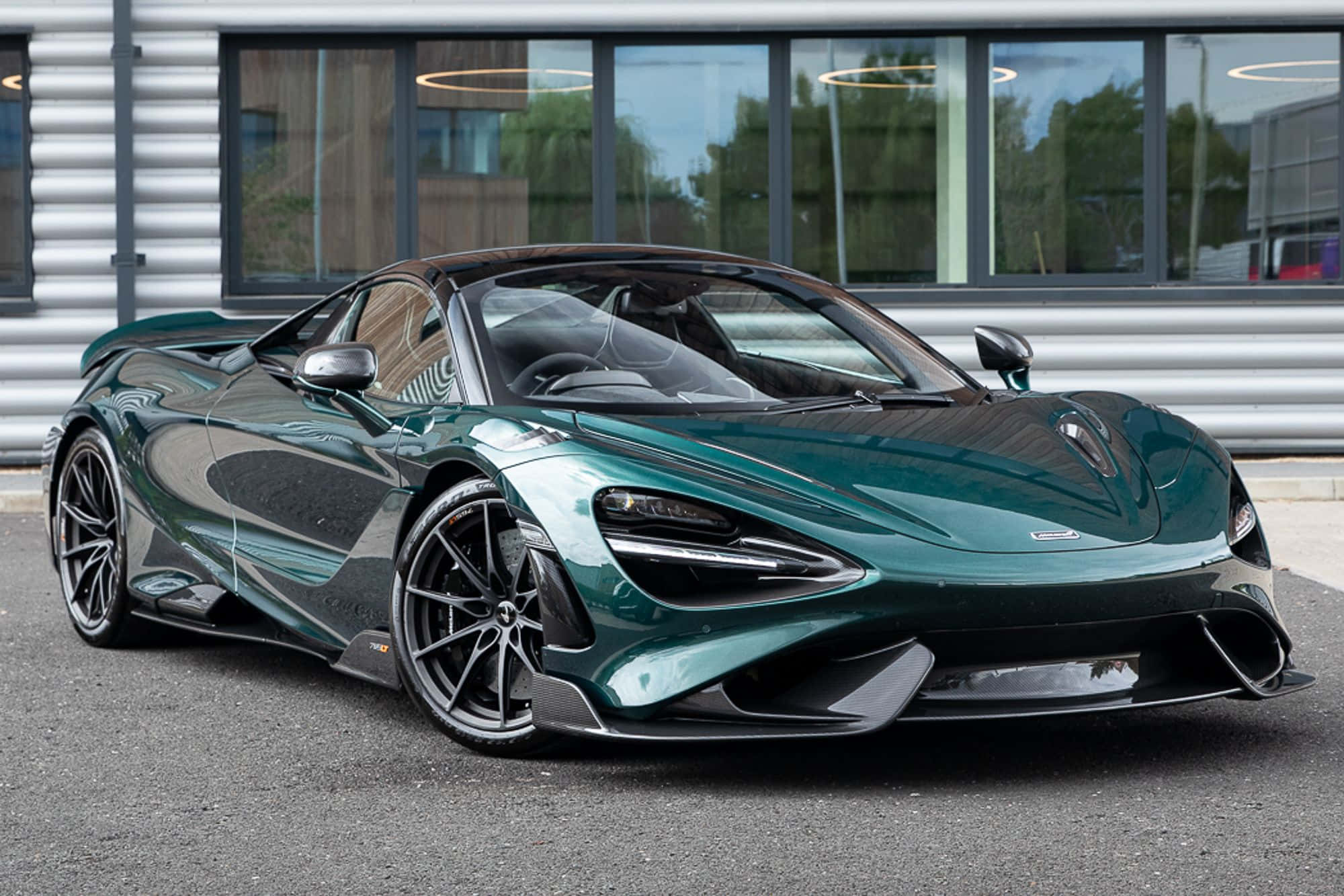 Mclaren 765lt 桌布 壁紙 — 一輛時尚的翡翠綠色McLaren 720S跑車停放在現代建築前的柏油路上，建築物有大型窗戶。